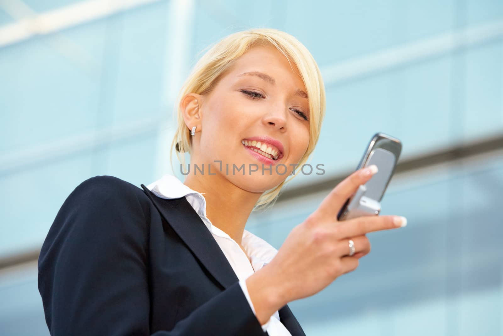 Businesswoman looking at mobile phone, smiling