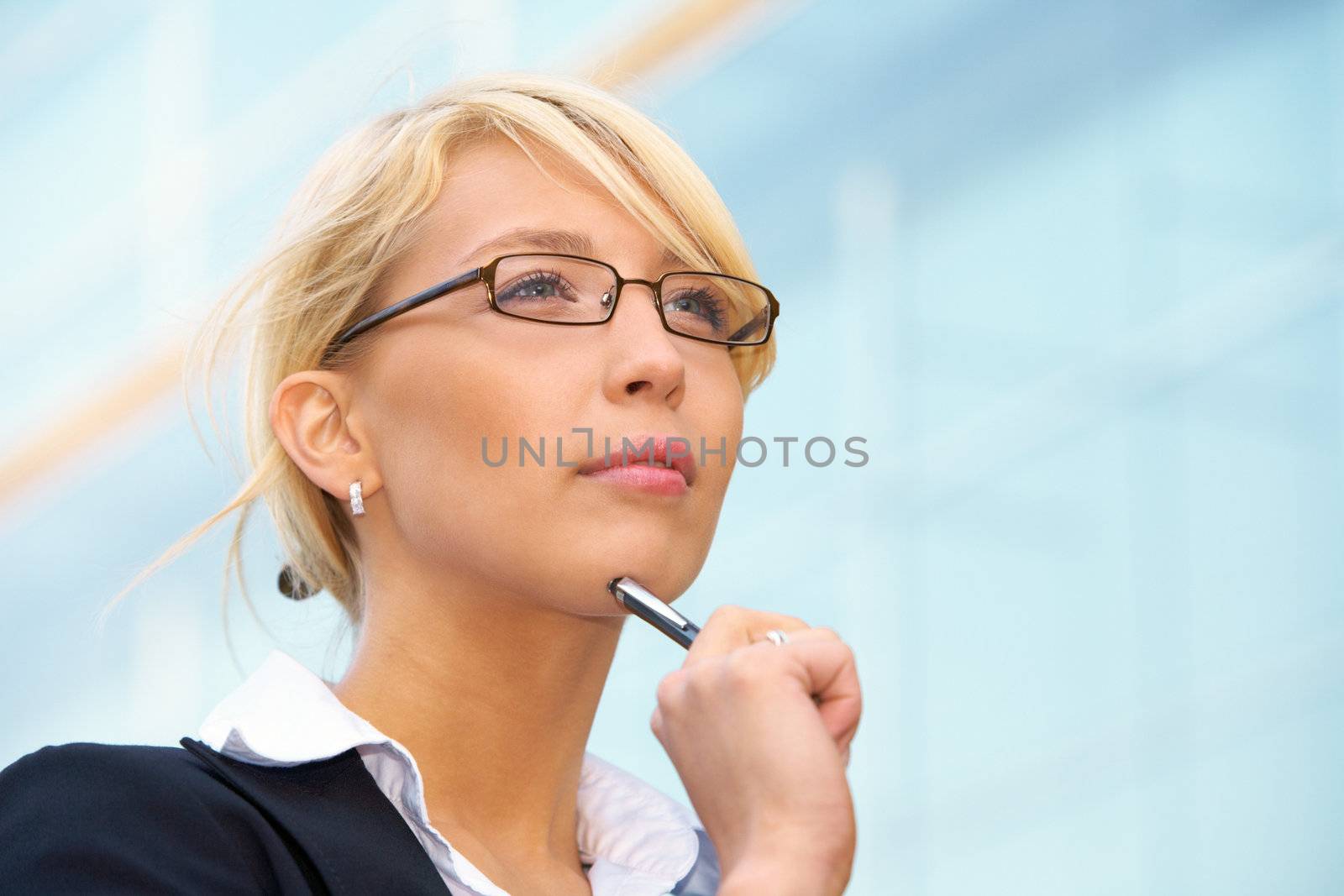 Young businesswoman holding pen outside office building, contemplating