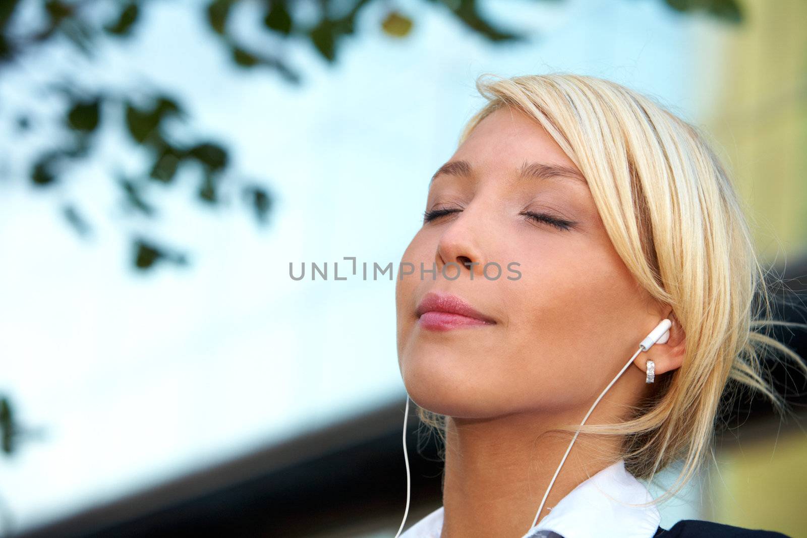 Young businesswoman wearing earphones in city, eyes closed