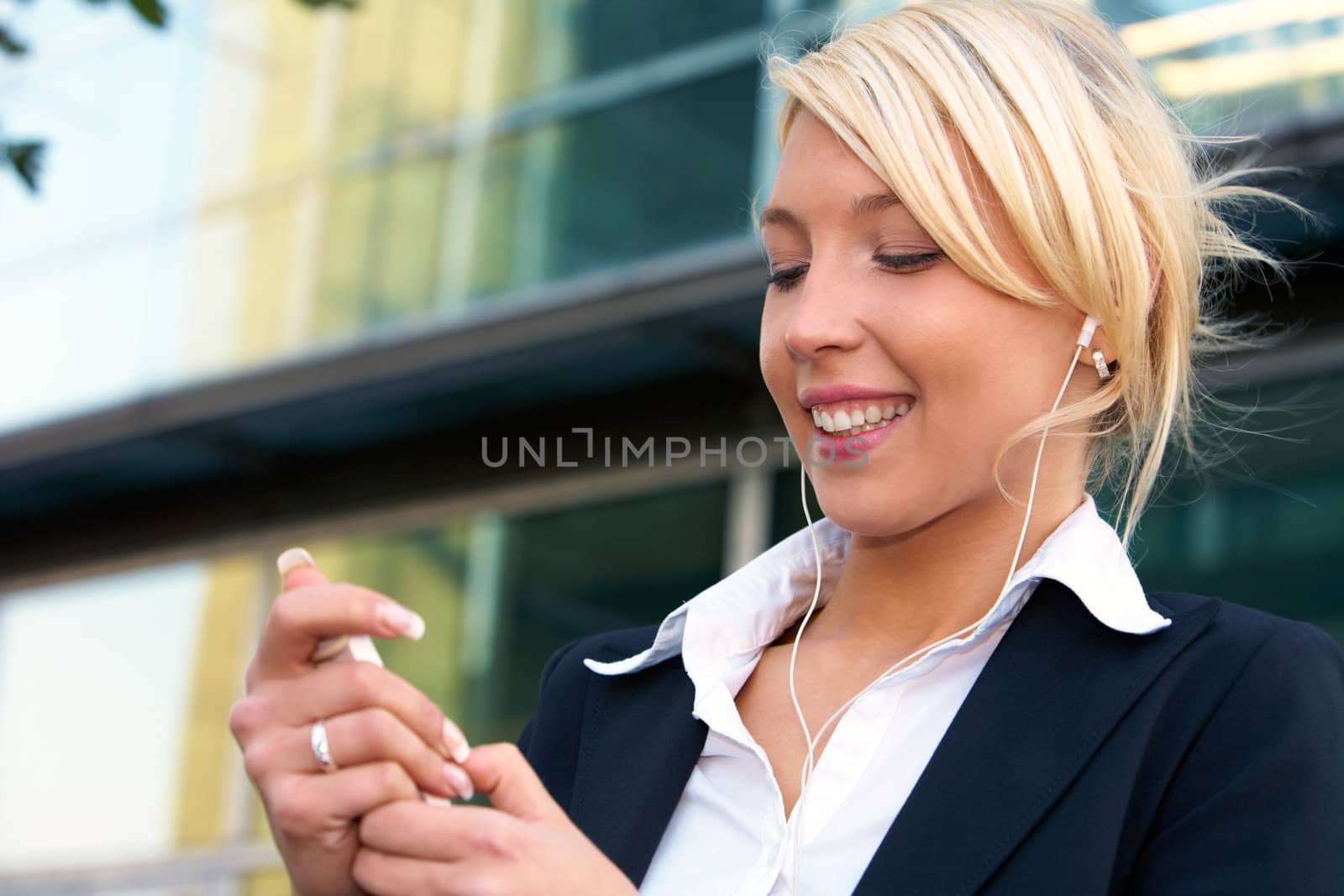 Young businesswoman wearing earphones, holding audio player device