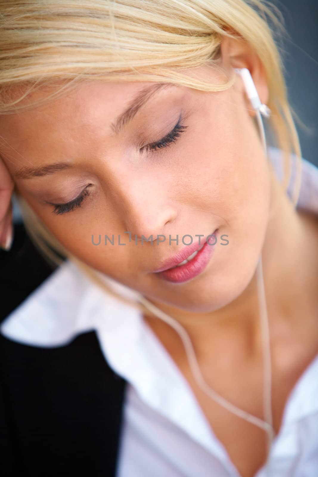 Young businesswoman wearing earphones with eyes closed, close-up
