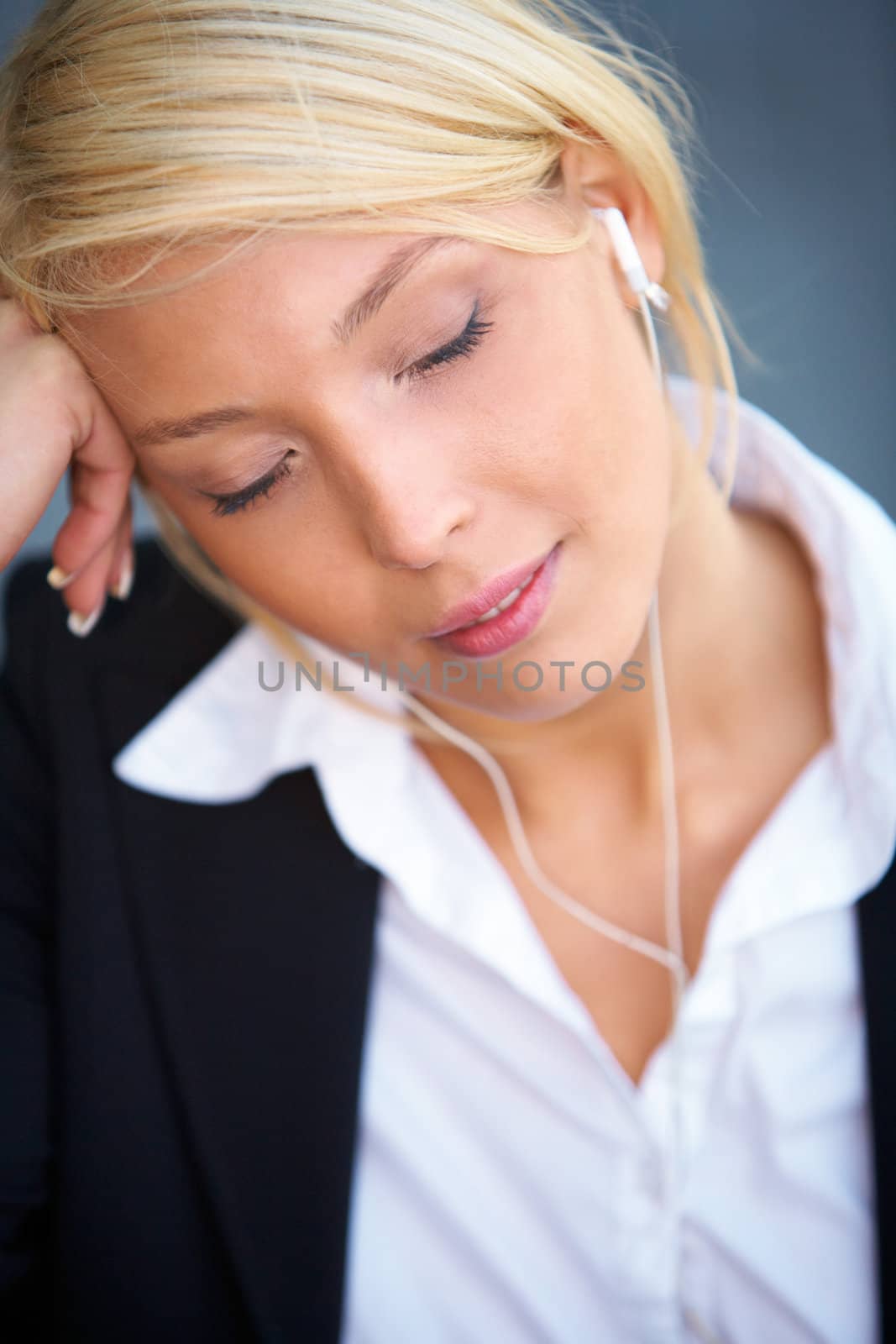 Young businesswoman wearing earphones with eyes closed