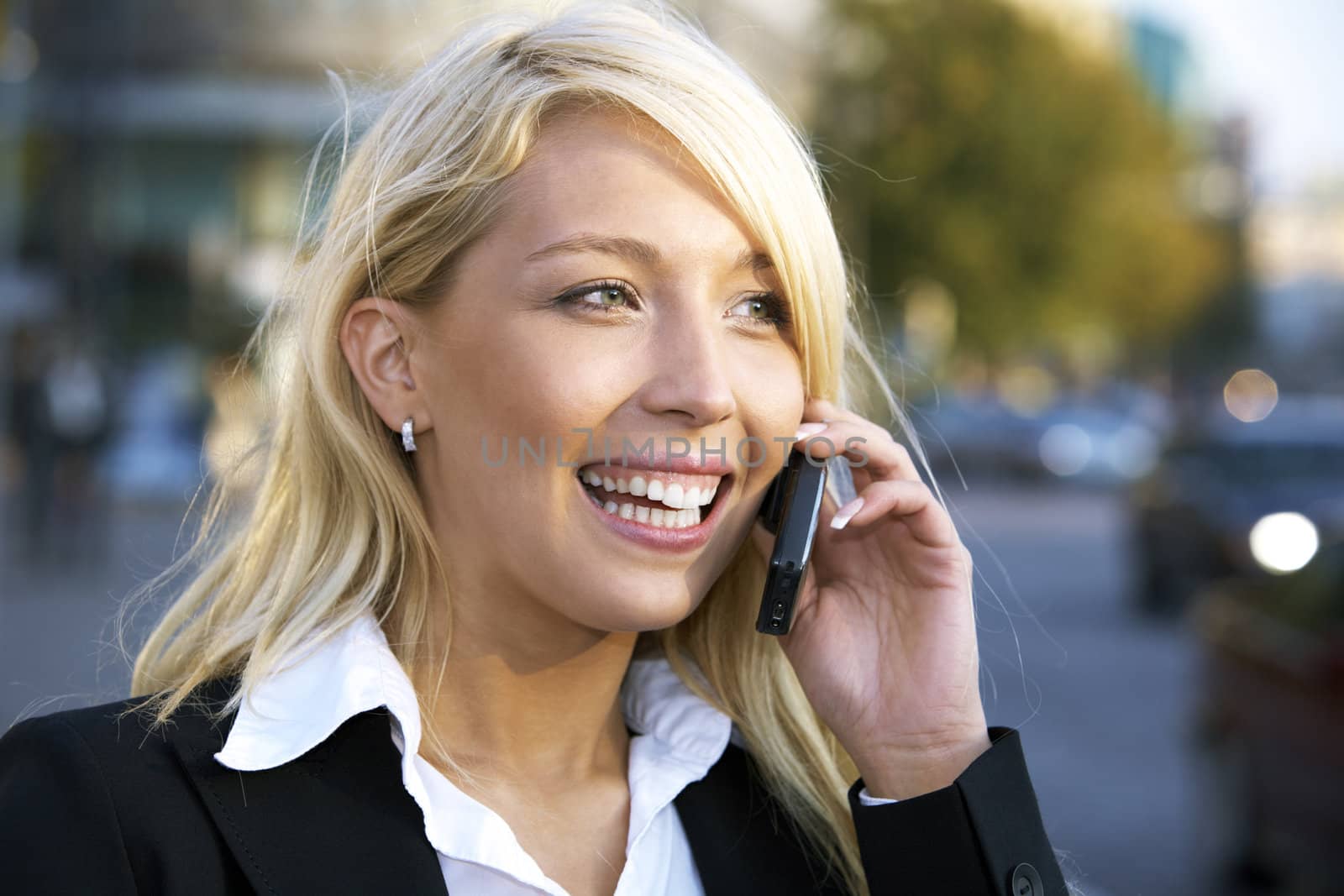 Young businesswoman smiling while using mobile phone in city street