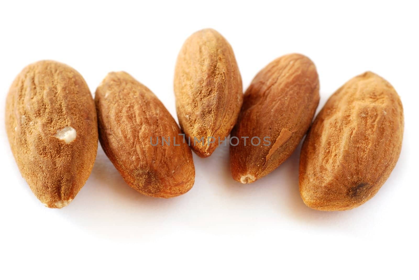 brown raw almonds over white background macro
