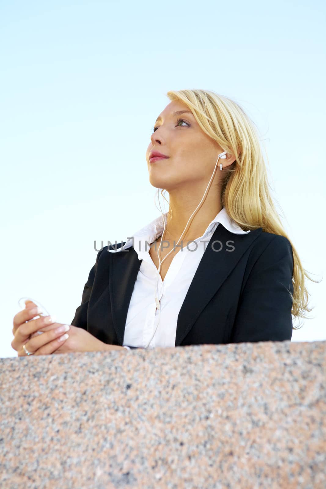Young businesswoman listening to audio player wearing earphones