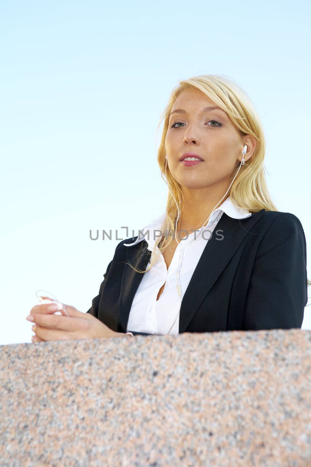 Young businesswoman looking at camera wearing earphones