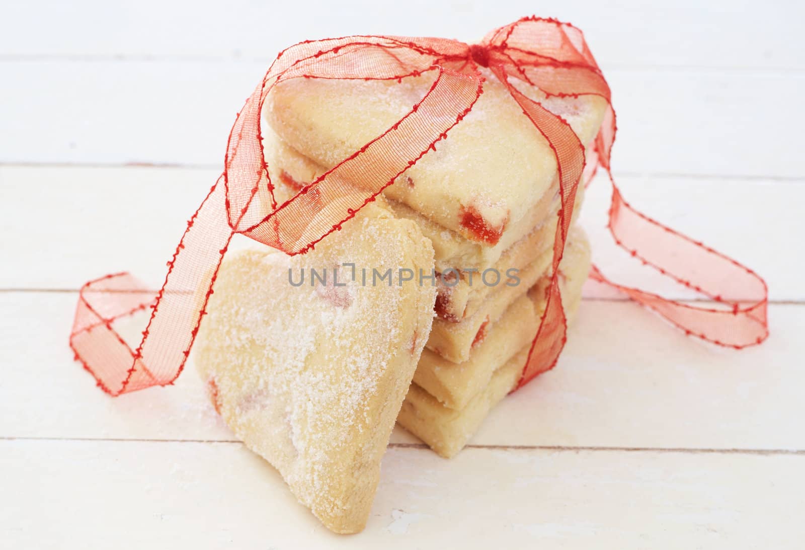 Heart shaped strawberry shortbread cookies wrapped in red ribbon on white background