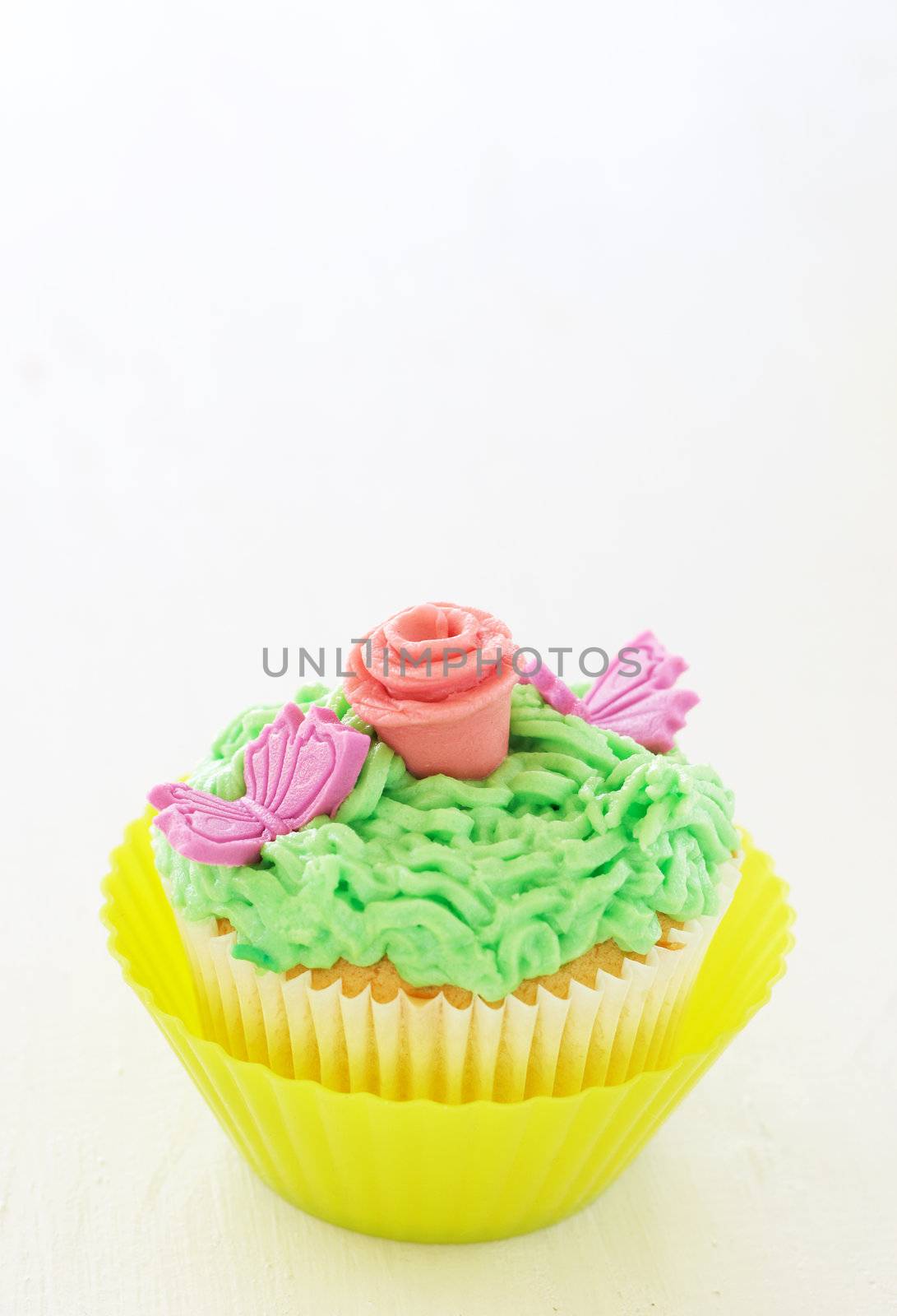 Vanilla cupcakes with buttercream icing and rose decorations on white background