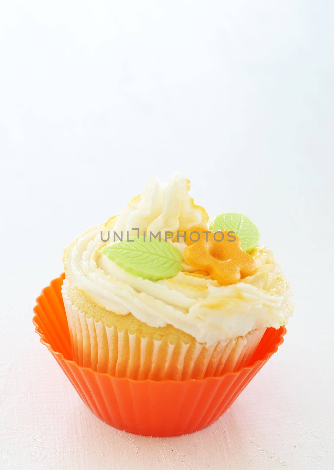 Vanilla cupcake with buttercream icing and flower decoration on white background