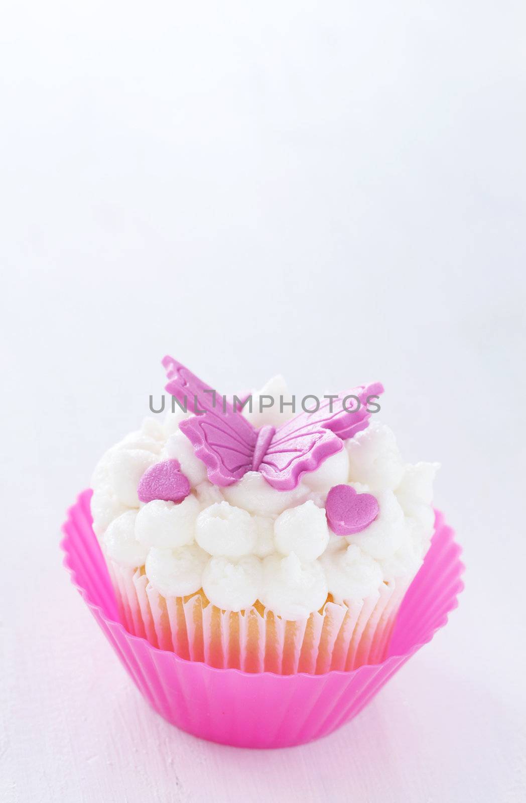 Vanilla cupcake with buttercream icing and butterfly decorations on white background