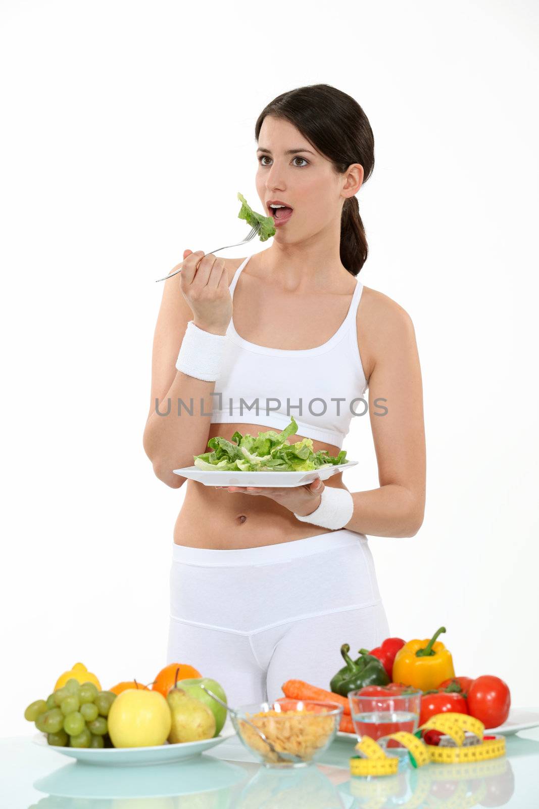 Woman in sportswear eating salad by phovoir