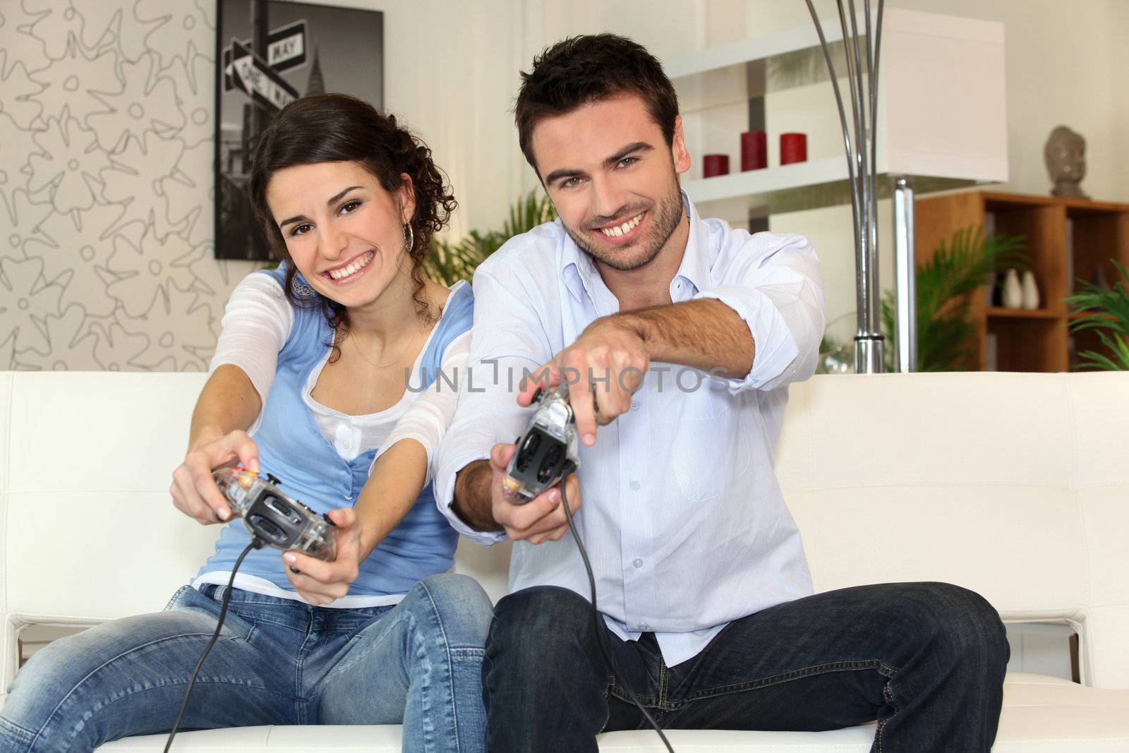 A couple having fun playing video games by phovoir