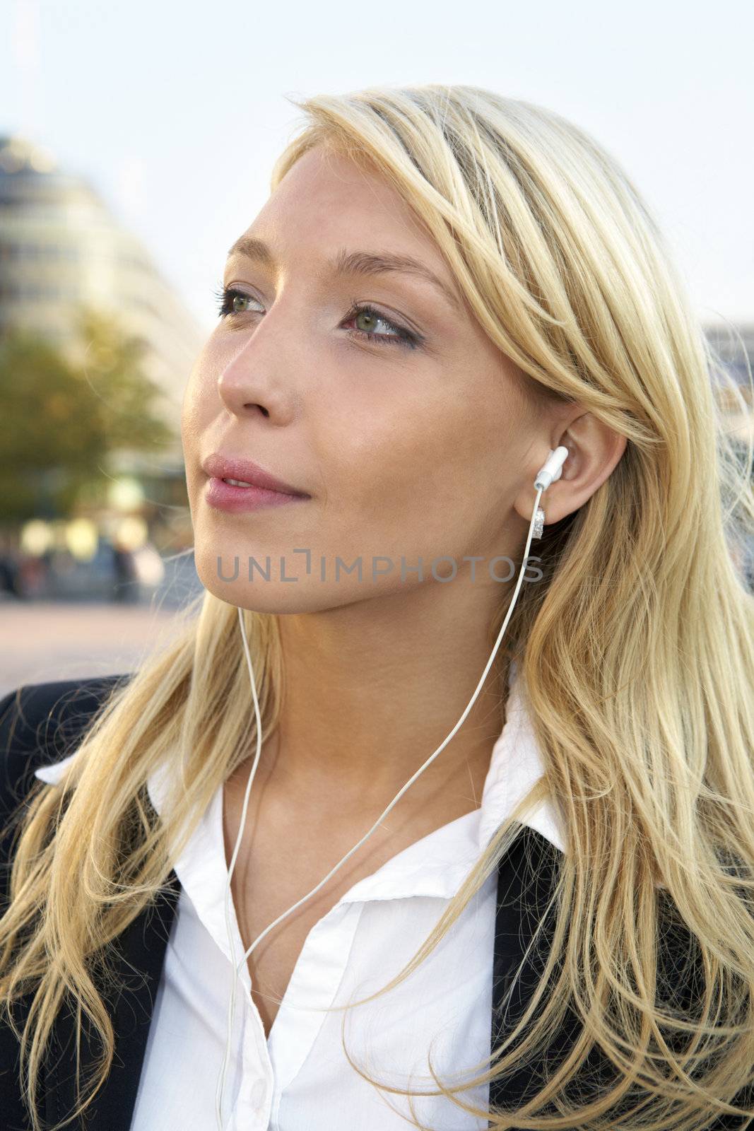 Young businesswoman wearing earphones in city street