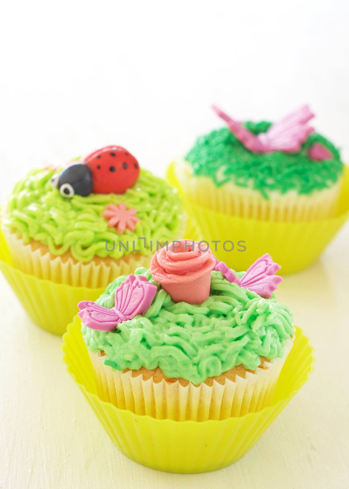 Vanilla cupcakes with buttercream icing and various decorations on white background