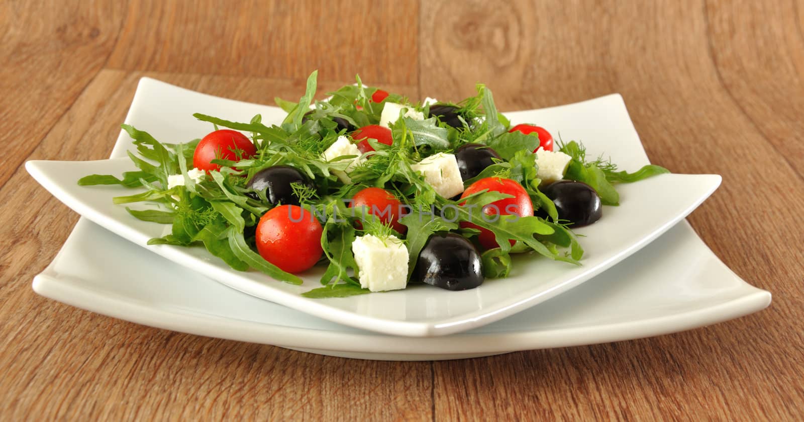 Salad of arugula with cherry tomatoes, slices of cheese and grapes