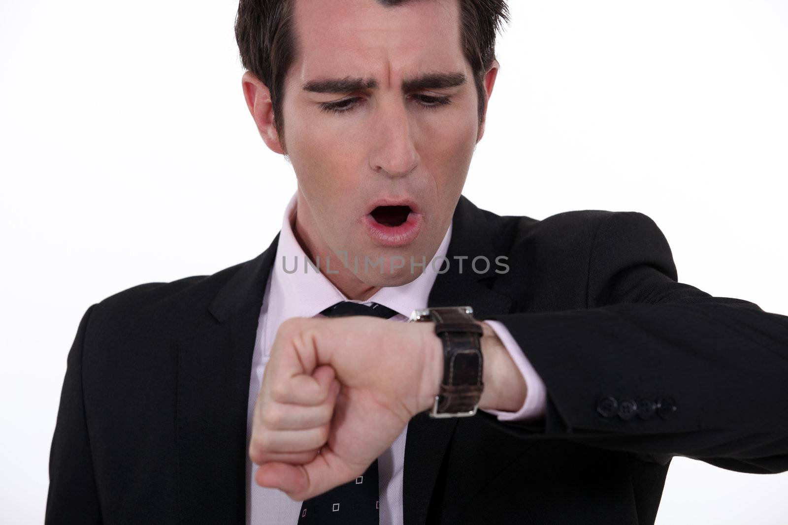businessman in a hurry looking at his watch by phovoir