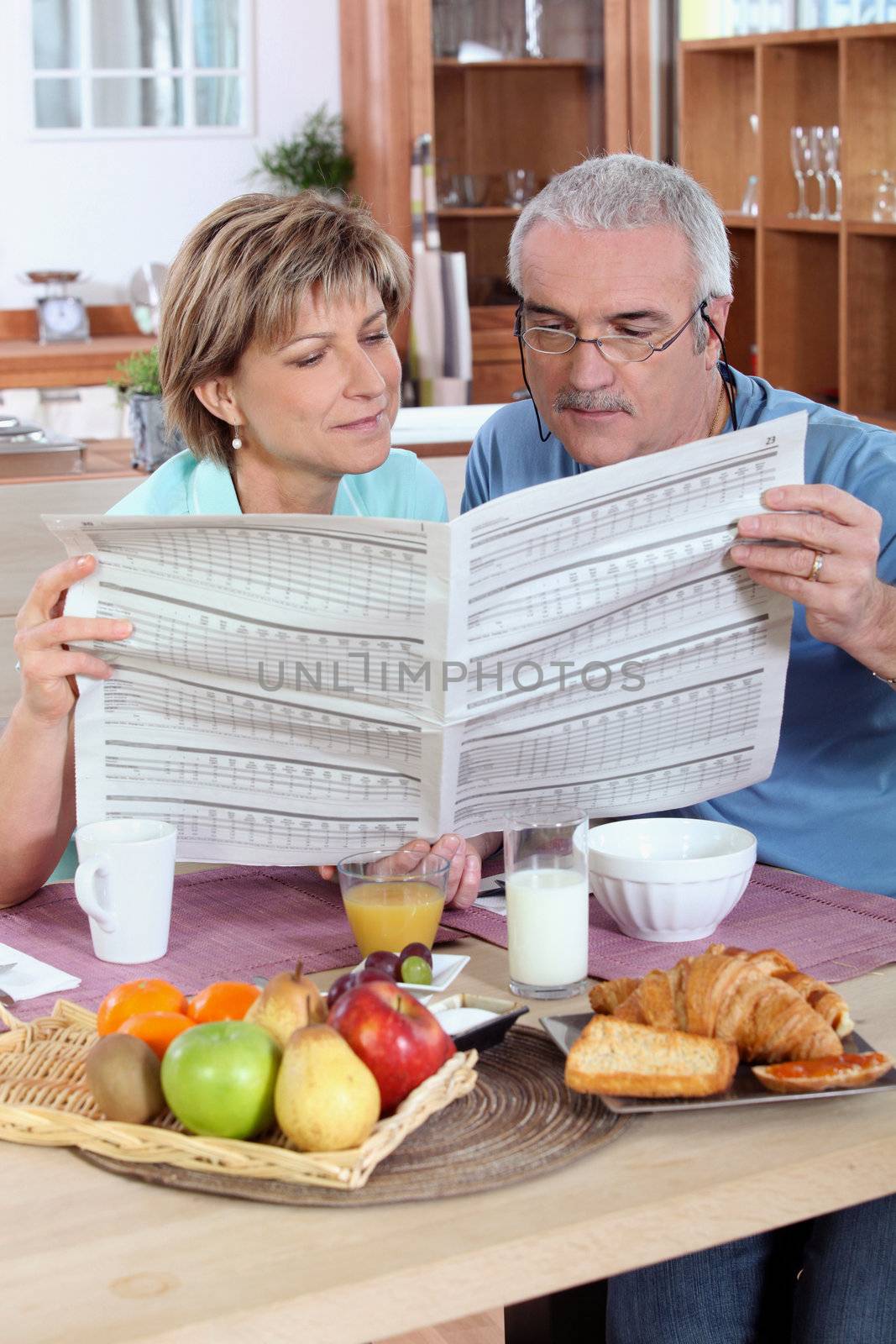 Couple reading the newspaper over breakfast