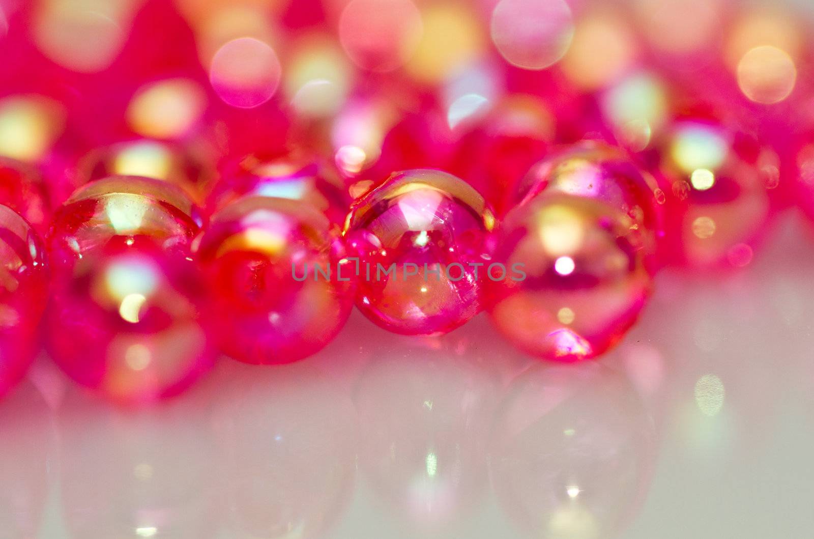 Red beads on white surface with mirror image