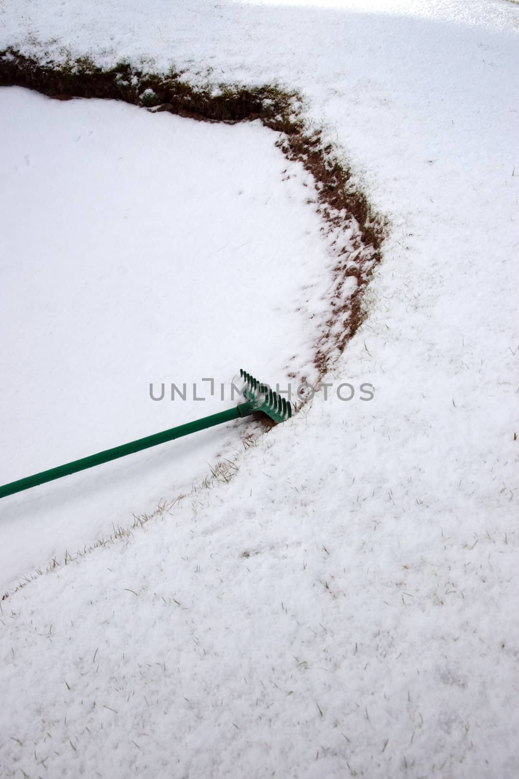 a green rake in a snow covered bunker on an irish golf course