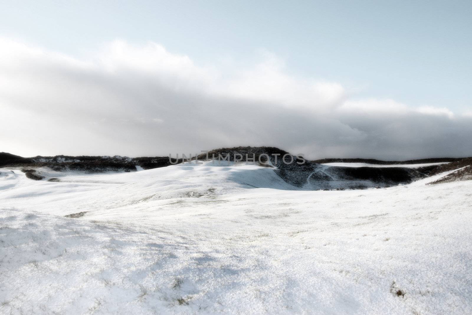 bunkers on a snow covered links golf course in ireland on a grey day in snowy winter weather