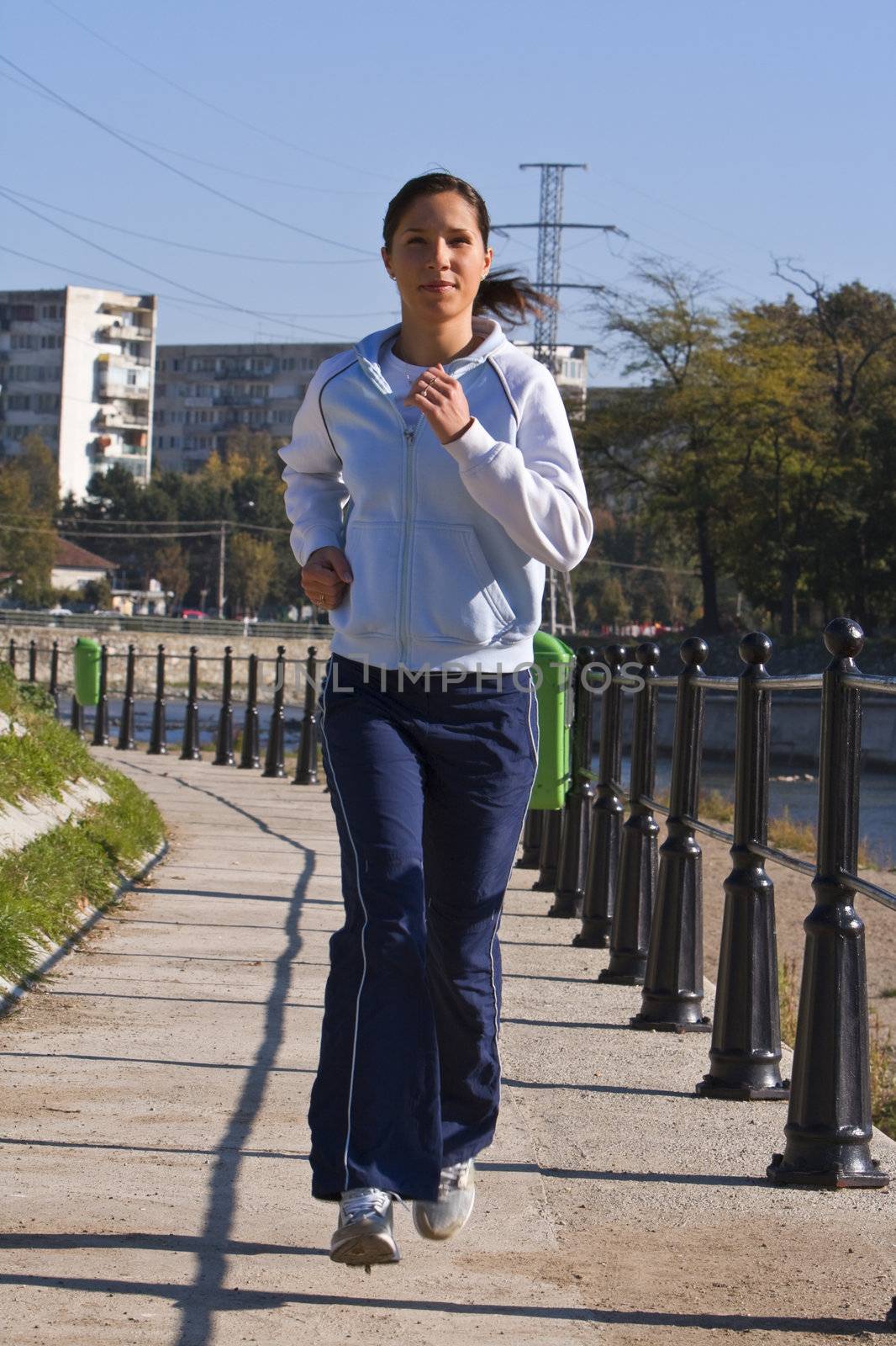 Young woman jogging in the morning on the riverside in a city.Shot with Canon 70-200mm f/2.8L IS USM
