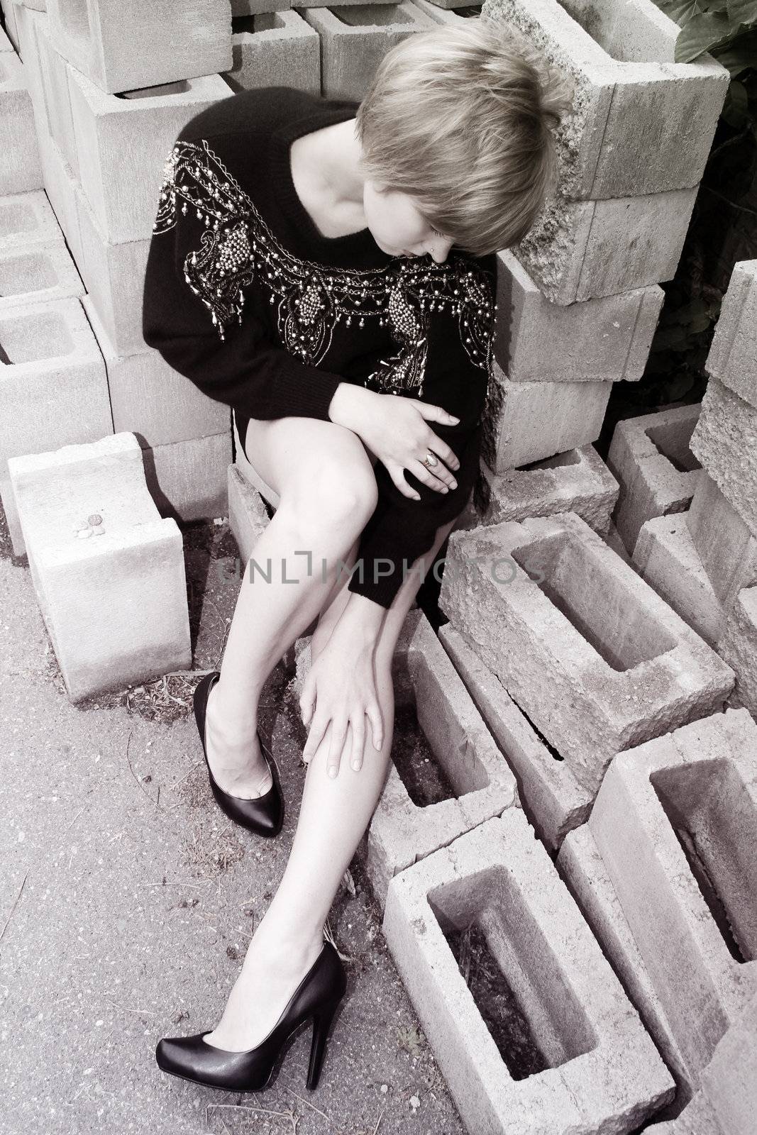 Beautiful blond female sitting on cement building blocks