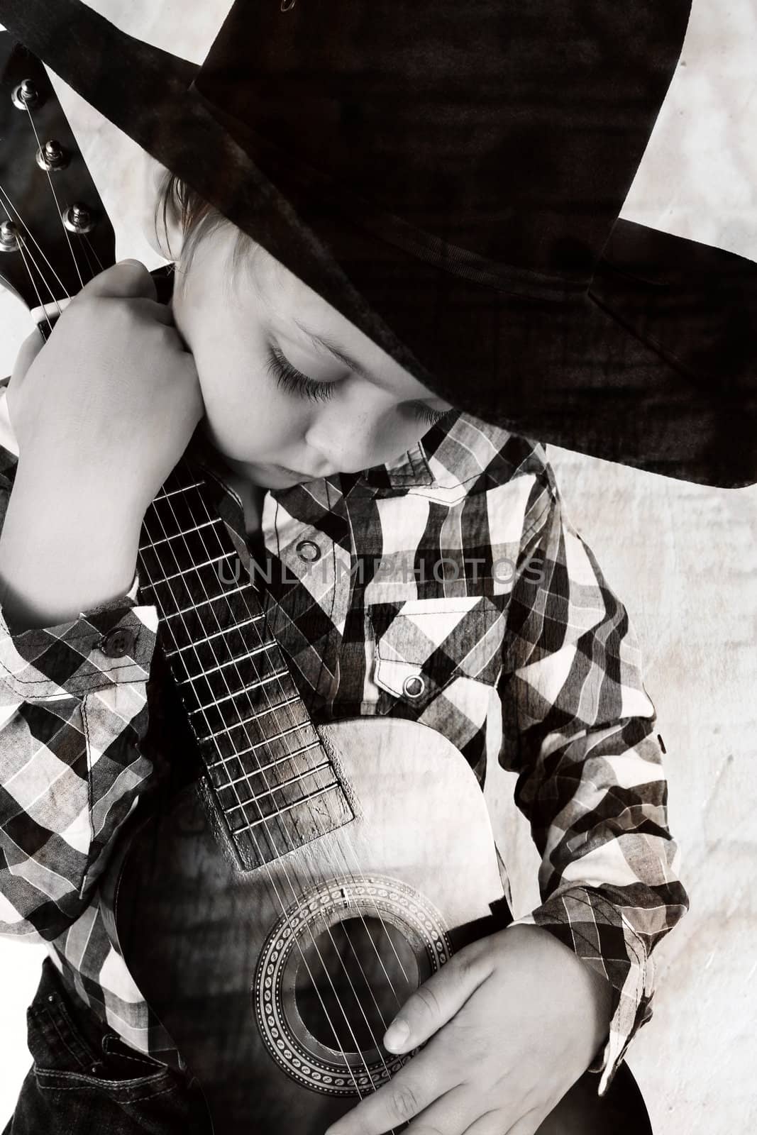 Beautiful blond cowboy wearing a hat holding guitar