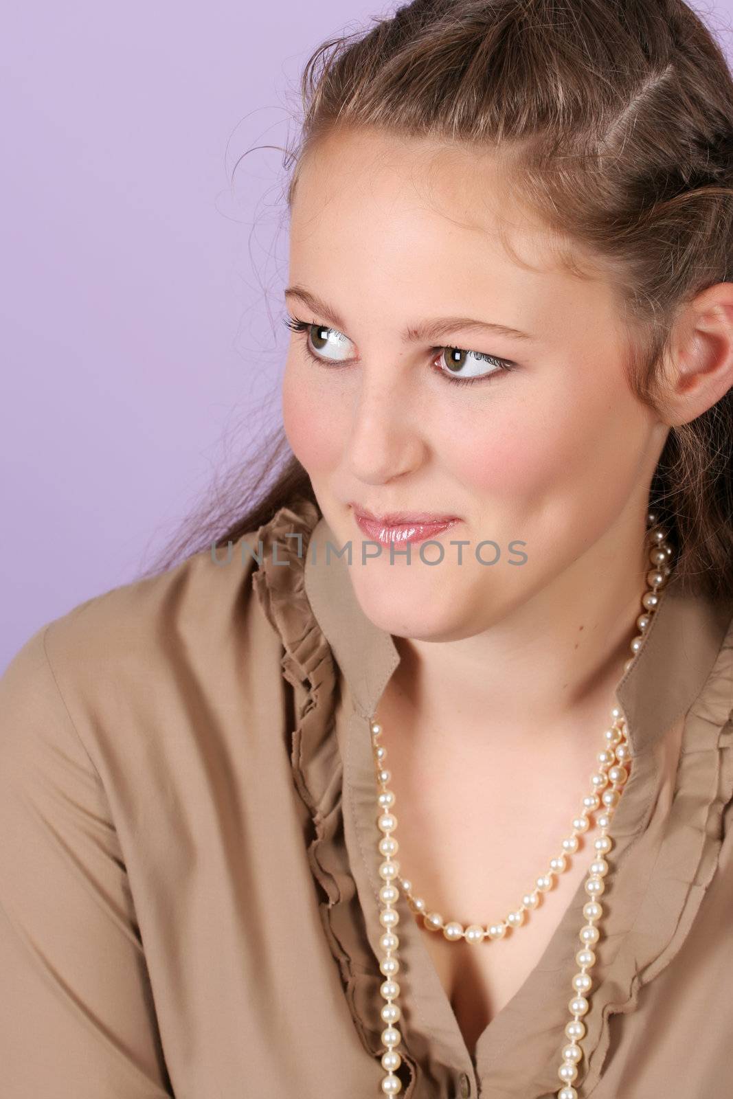 Beautiful teenage female against purple background, wearing pearls