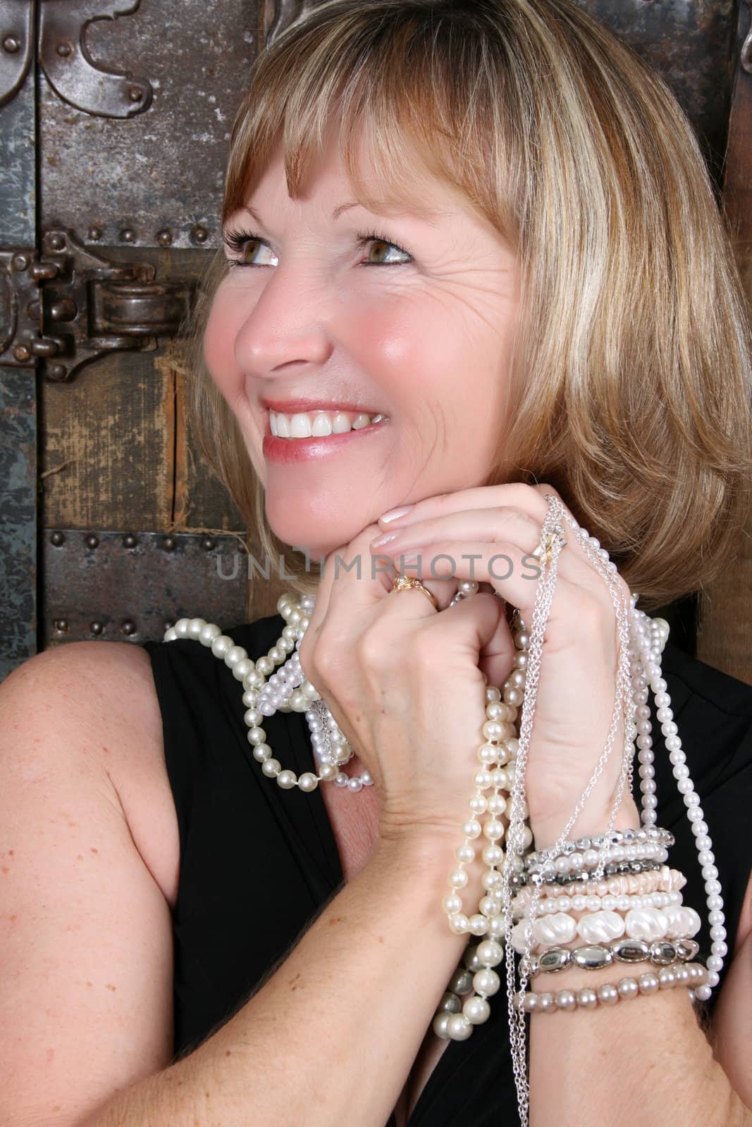 Beautiful blond female sitting against an antique trunk wearing pearls 