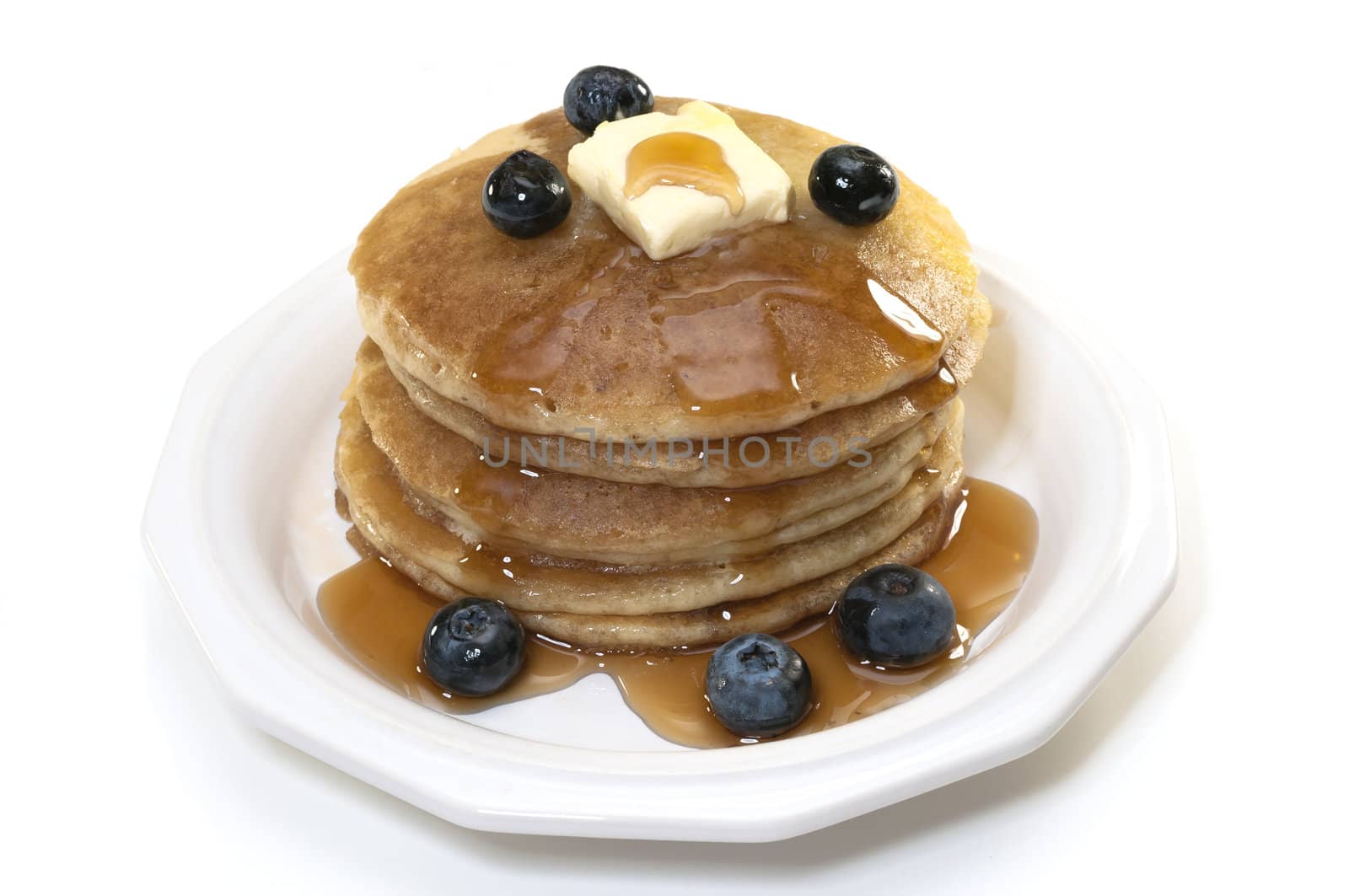 Pancakes with blueberries, syrup, and butter isolated on white background.