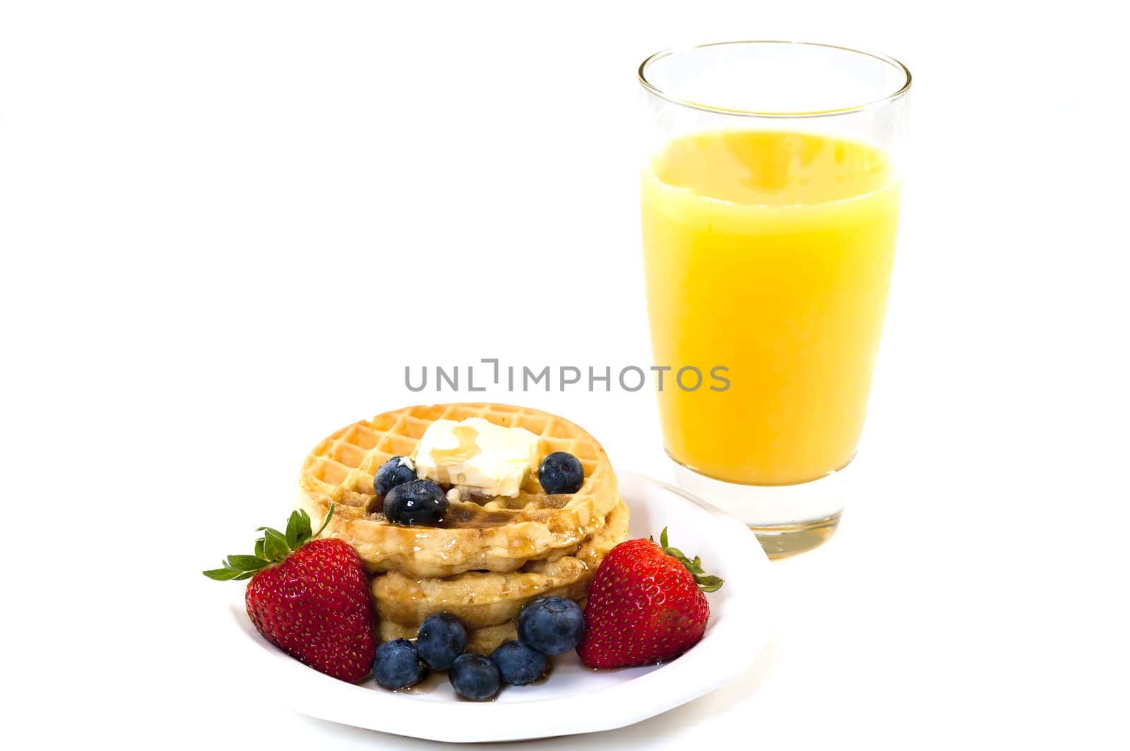 Stack of waffles, blueberries, and strawberries syrup, butter, and orange juice.   Isolated on white background.