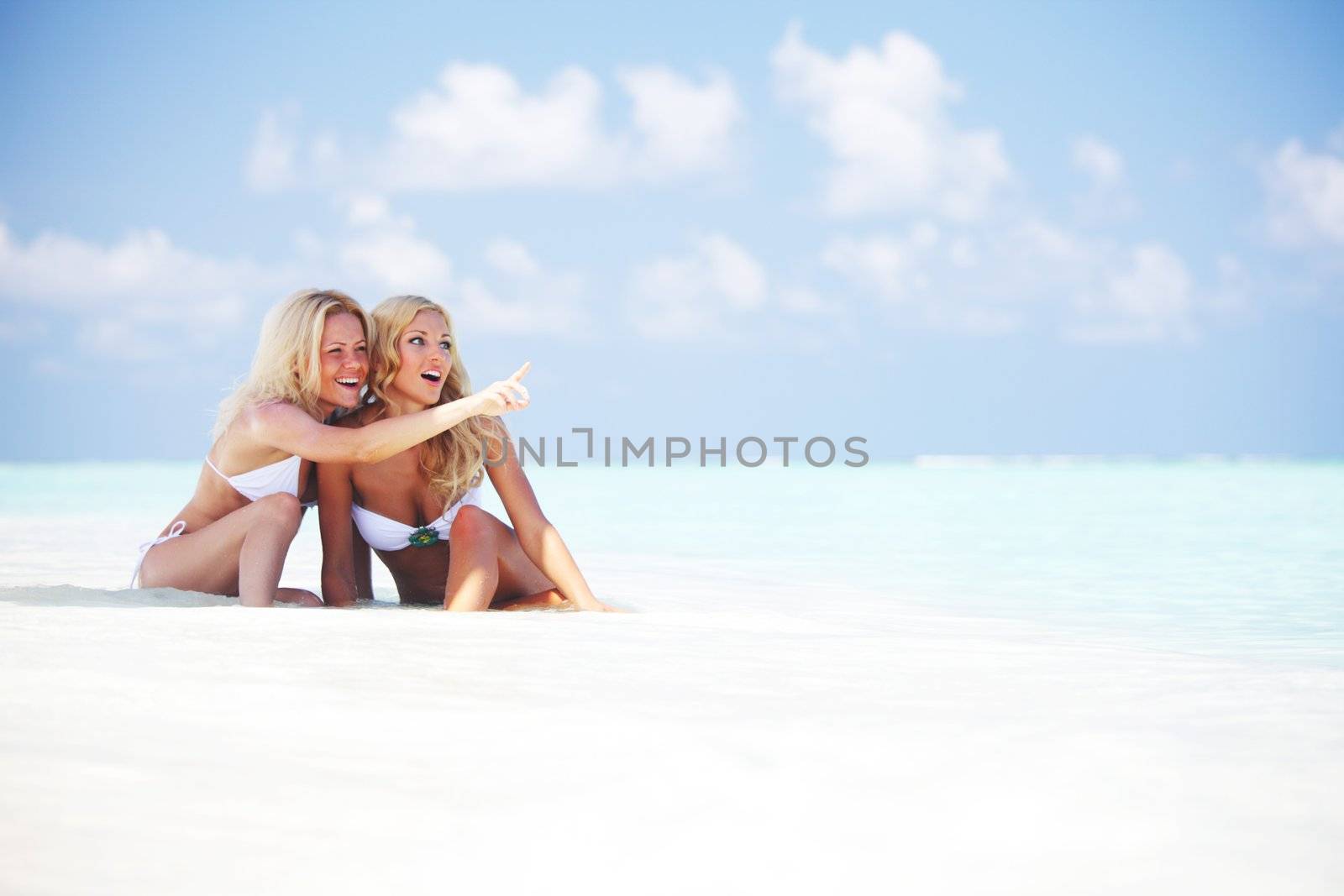 Two girls sitting on the ocean coast