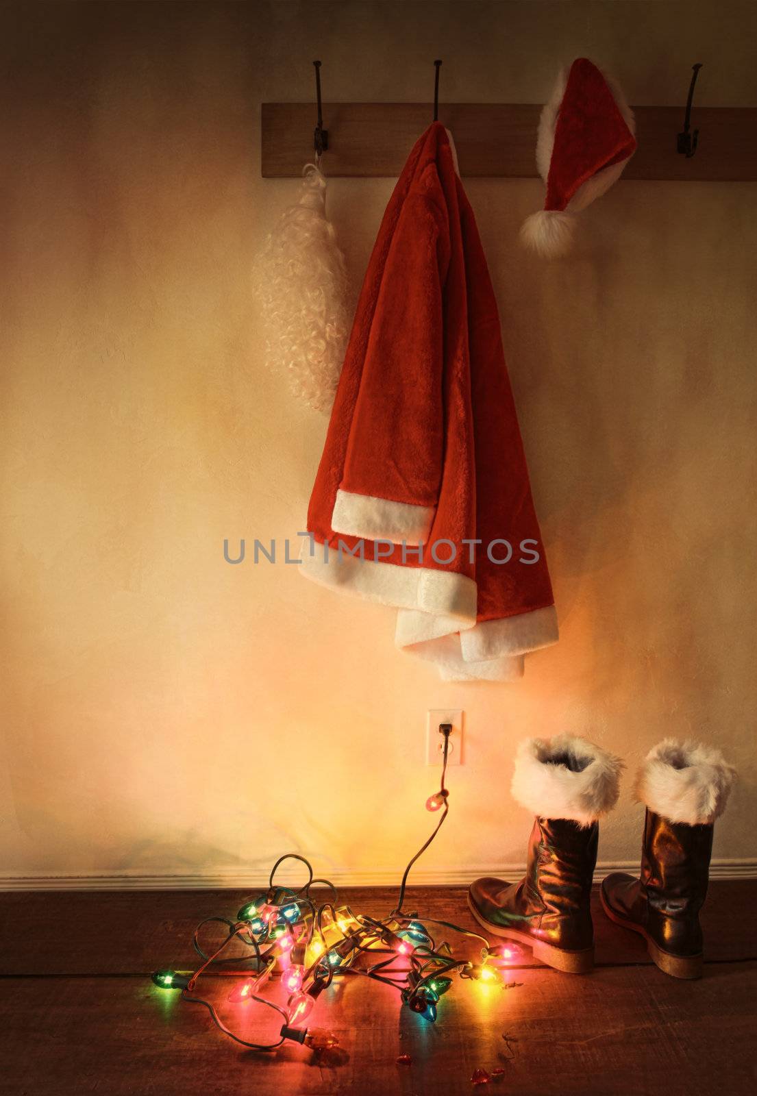 Santa costume hanging on coat hook with christmas lights on floor