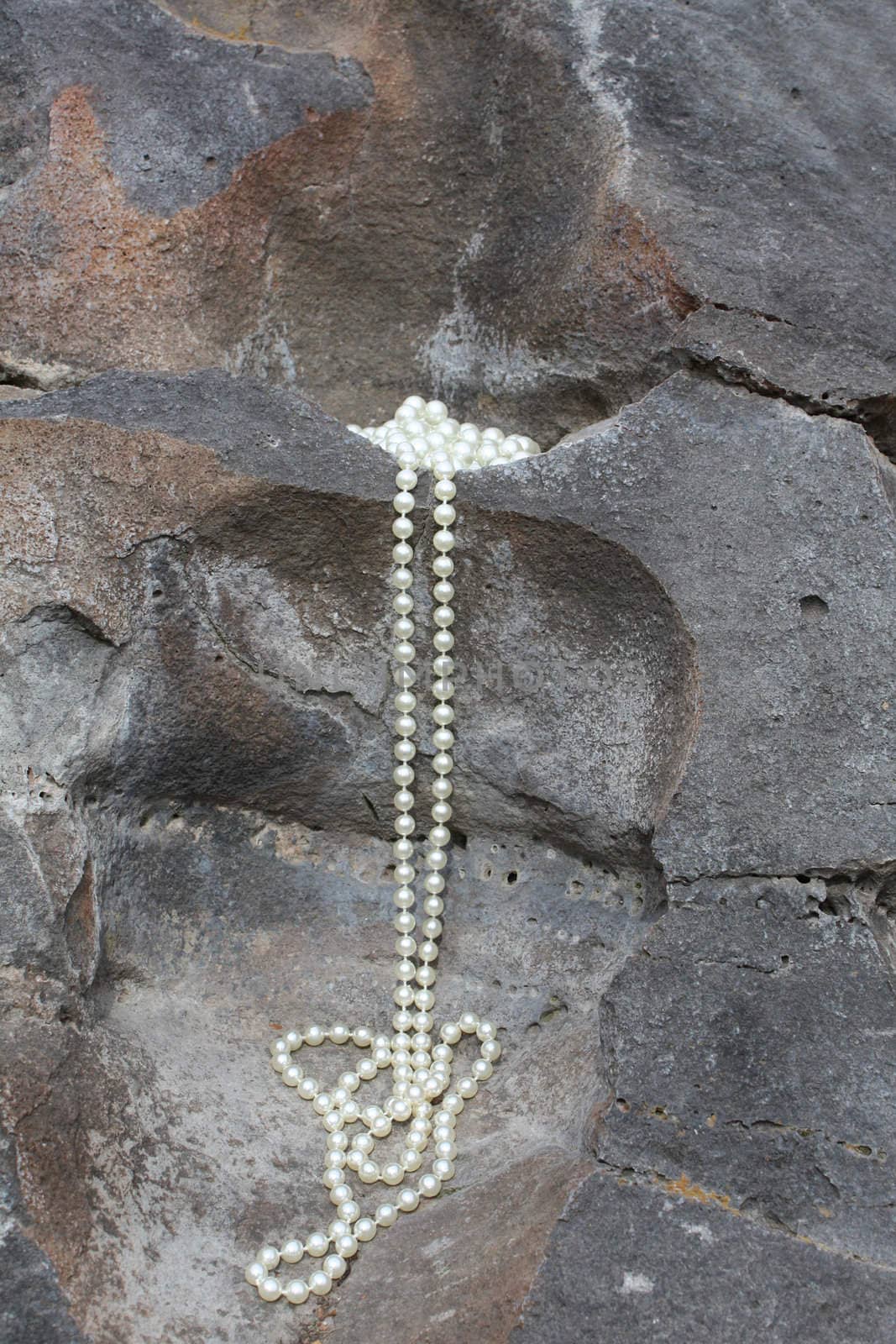 Long pearl necklace flowing from a rock