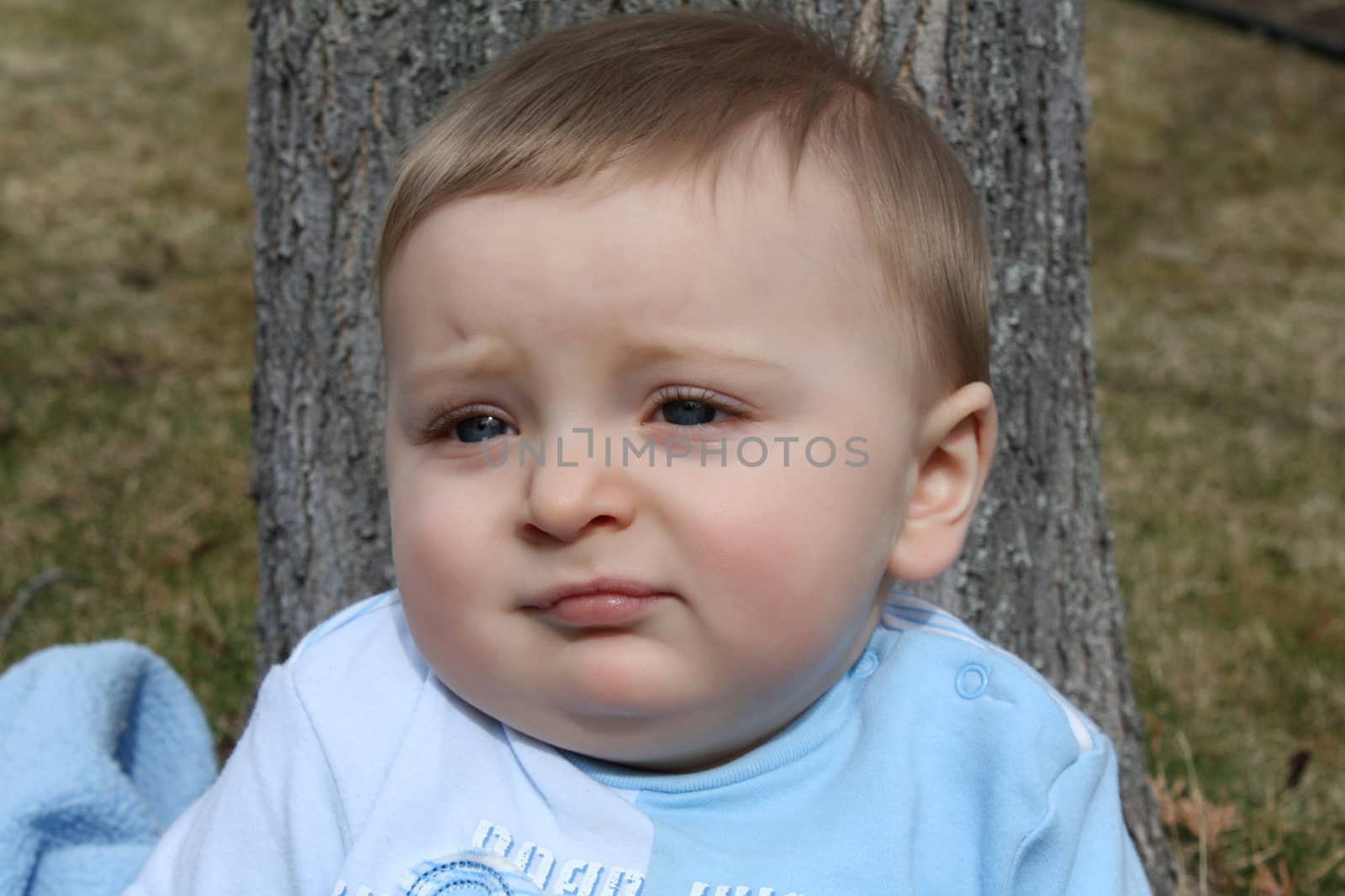 Adorable baby boy sitting outside in the sunny garden