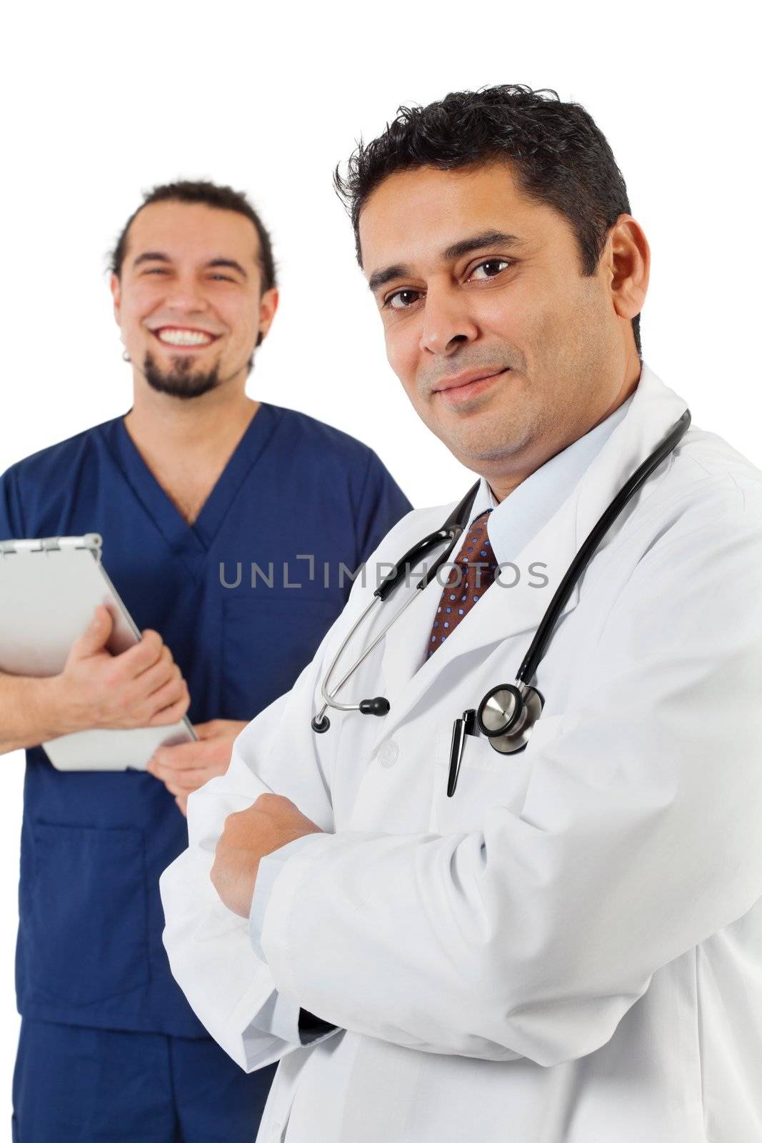 Photo of confident Indian doctor standing with male nurse in background. Focus is on doctor on right.