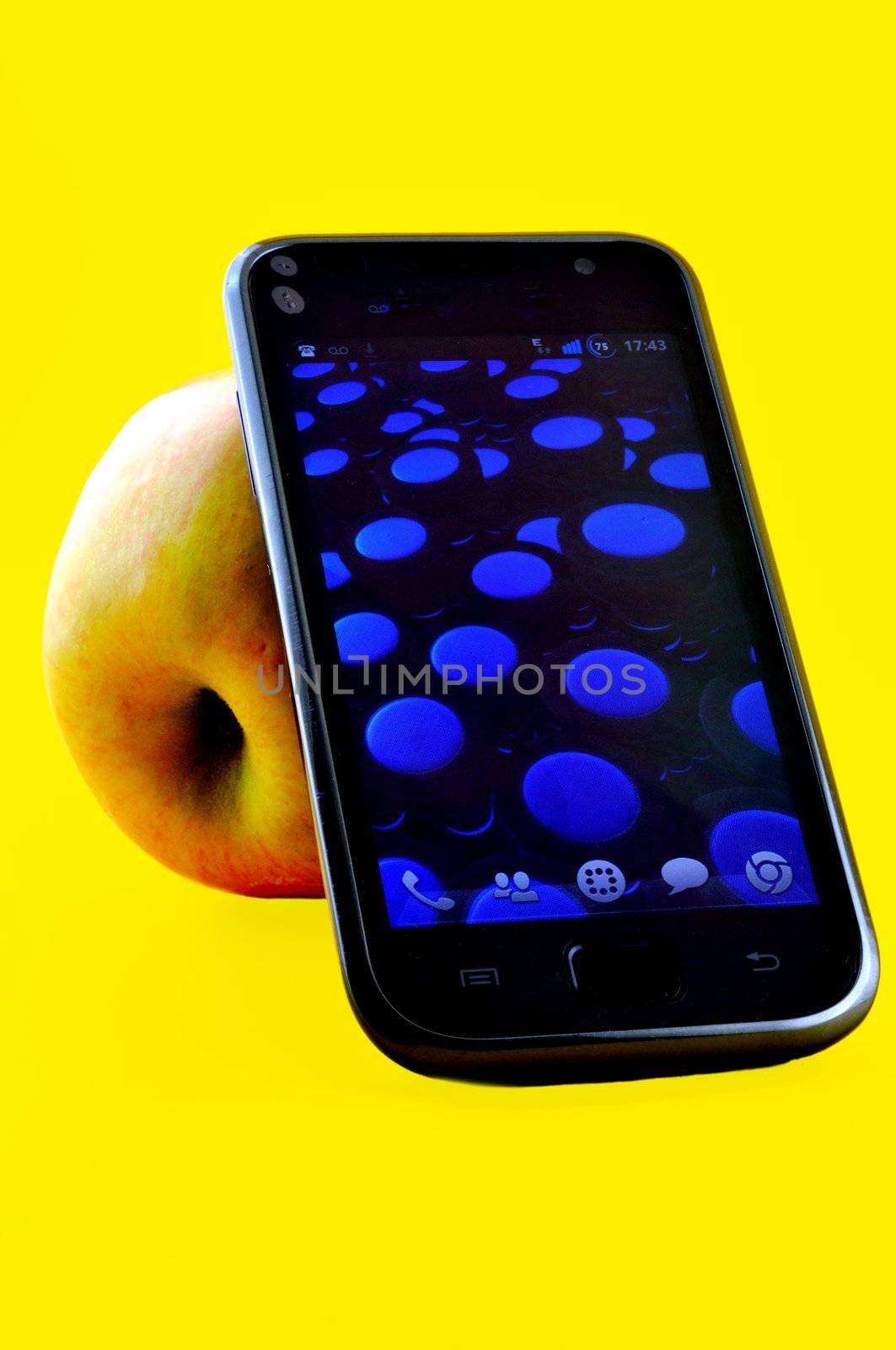 Mobile phone and apple, on which he relies, photographed against a yellow background
