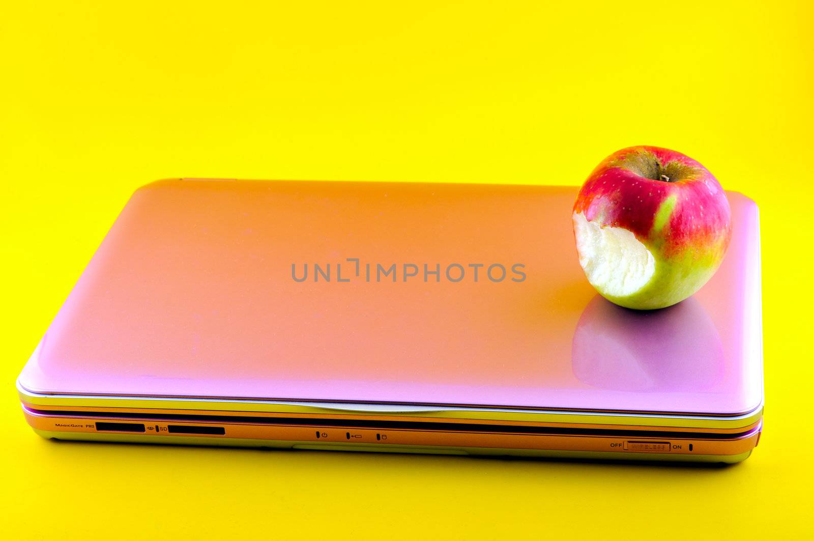 Pink computer that is bitten apple, photographed against a yellow background