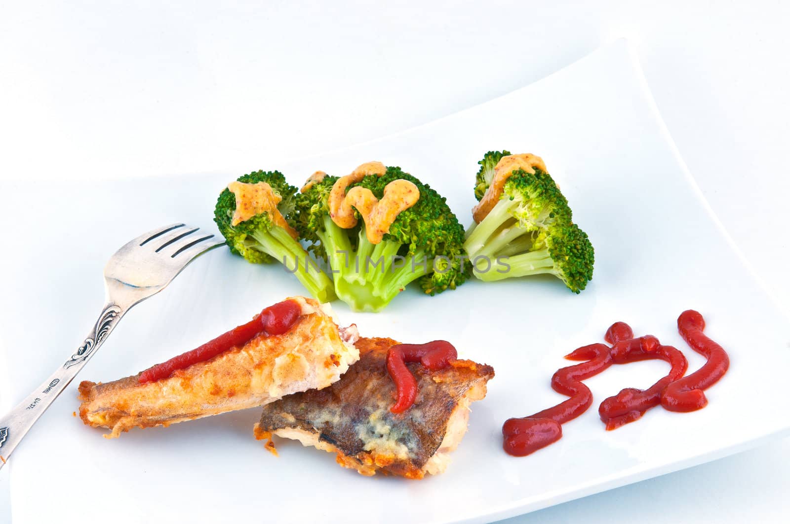 Fried fish poured ketchup, not near a plate with a grainy mustard broccoli