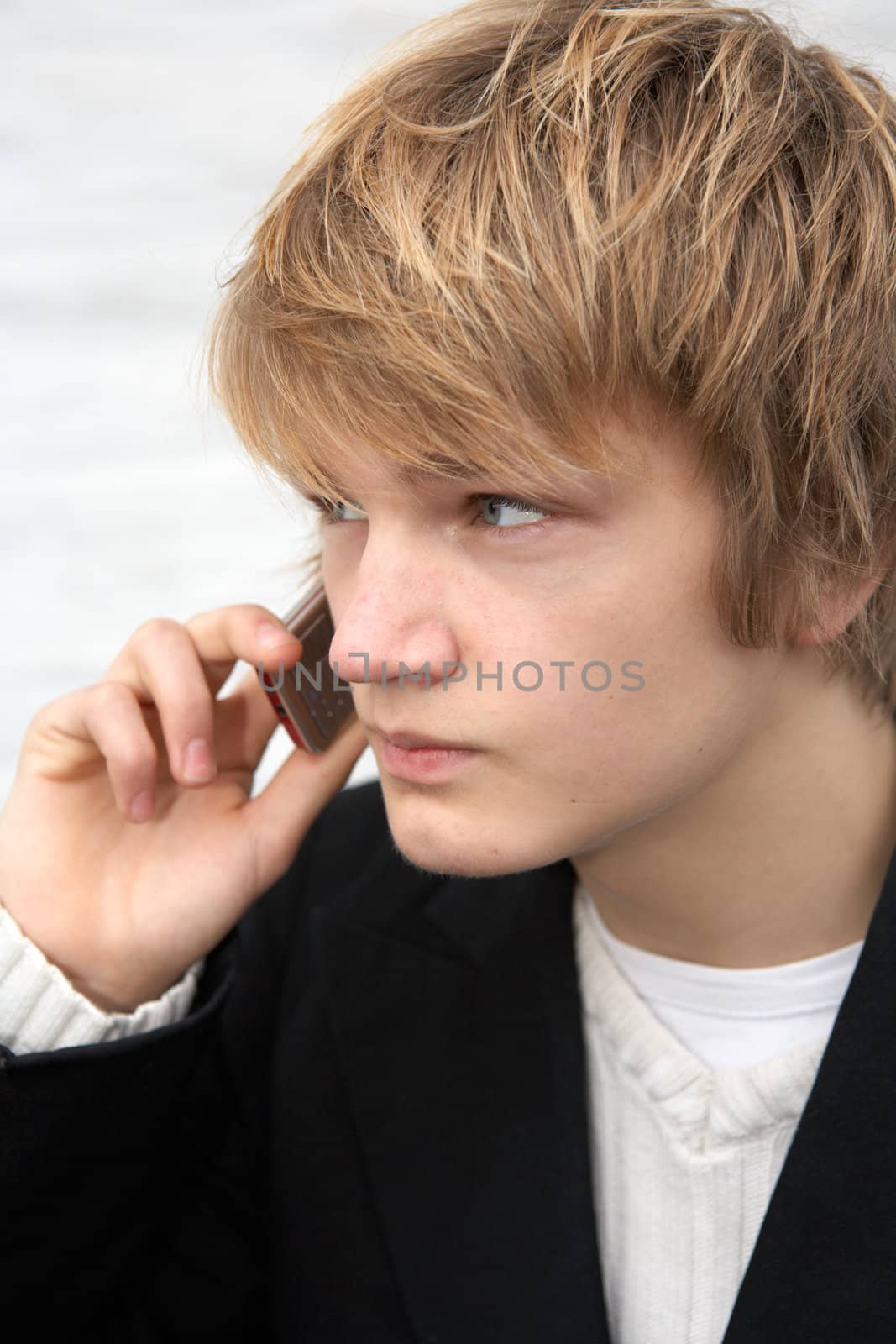 Teenage boy with mobile phone by white wall, close-up