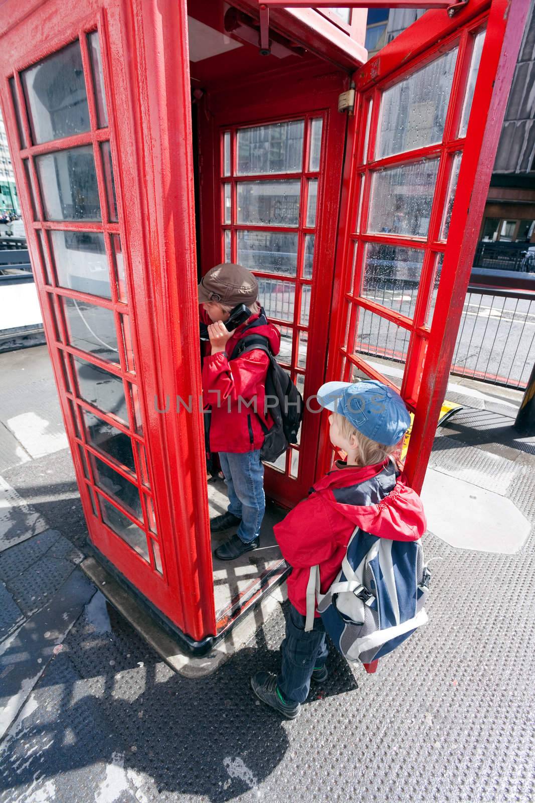 Boy talking in pay phone box by ints