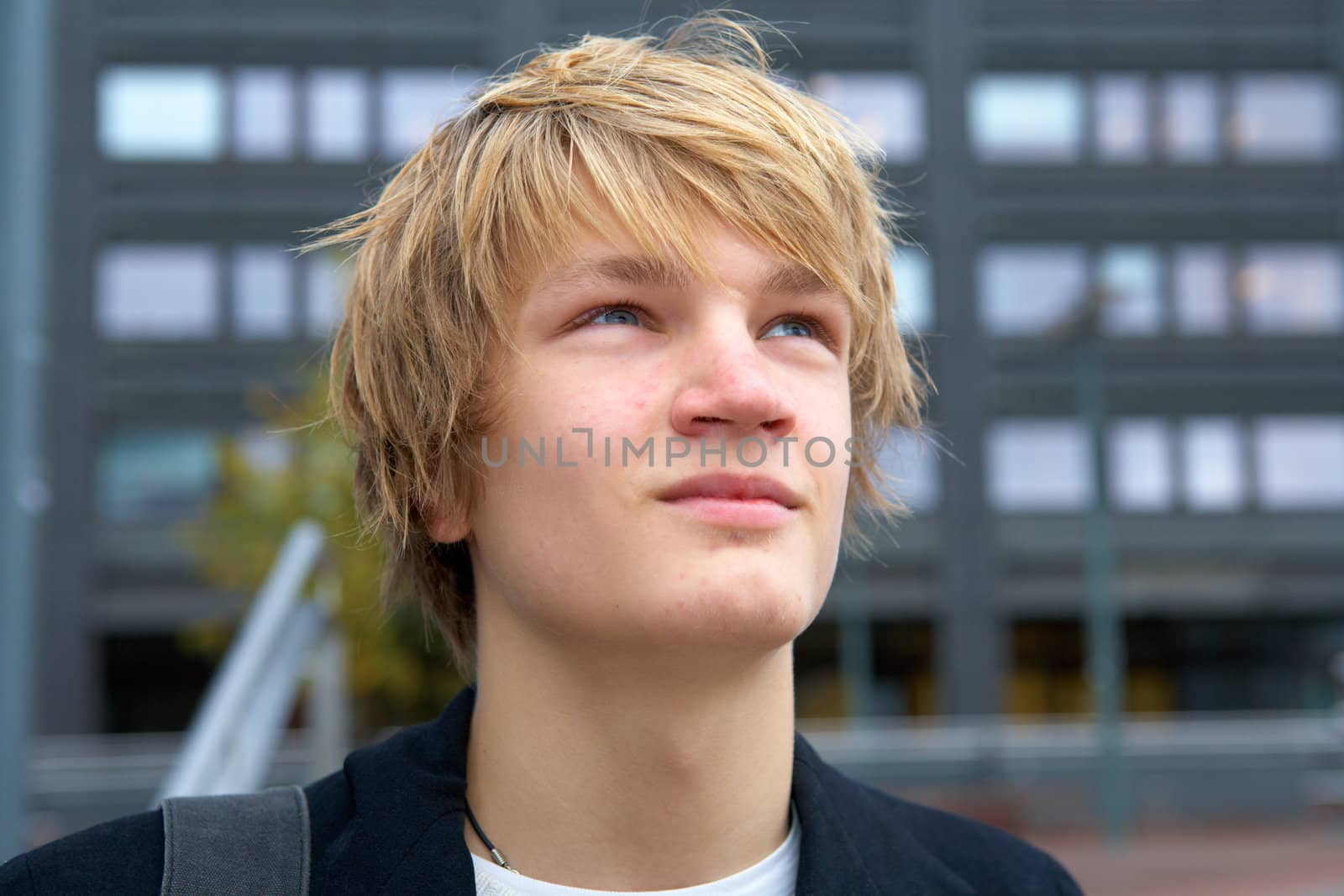 Portrait of confident teenage boy outdoor in city, looking up