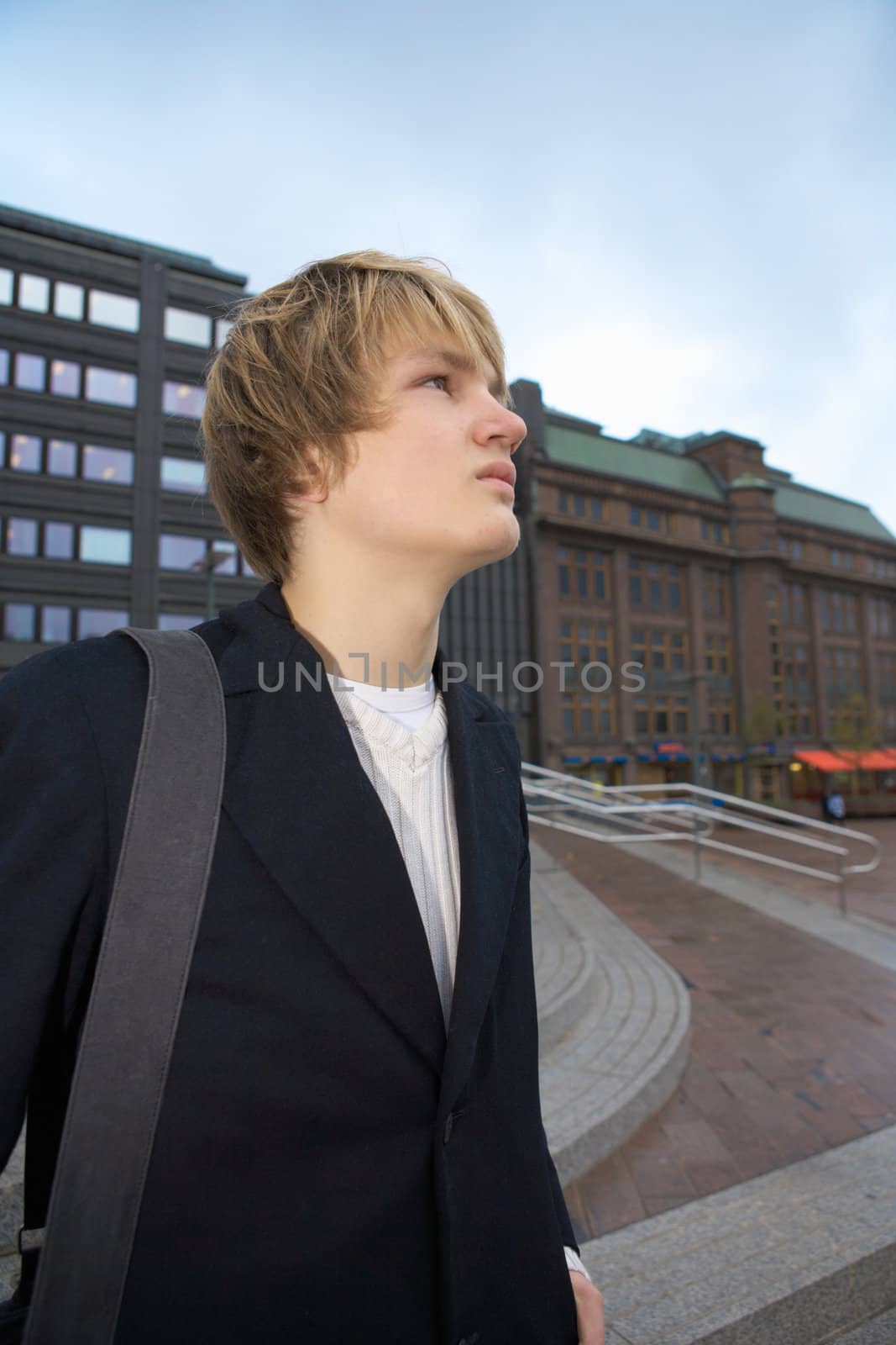 Side portrait of teenage boy in city, carrying shoulder bag