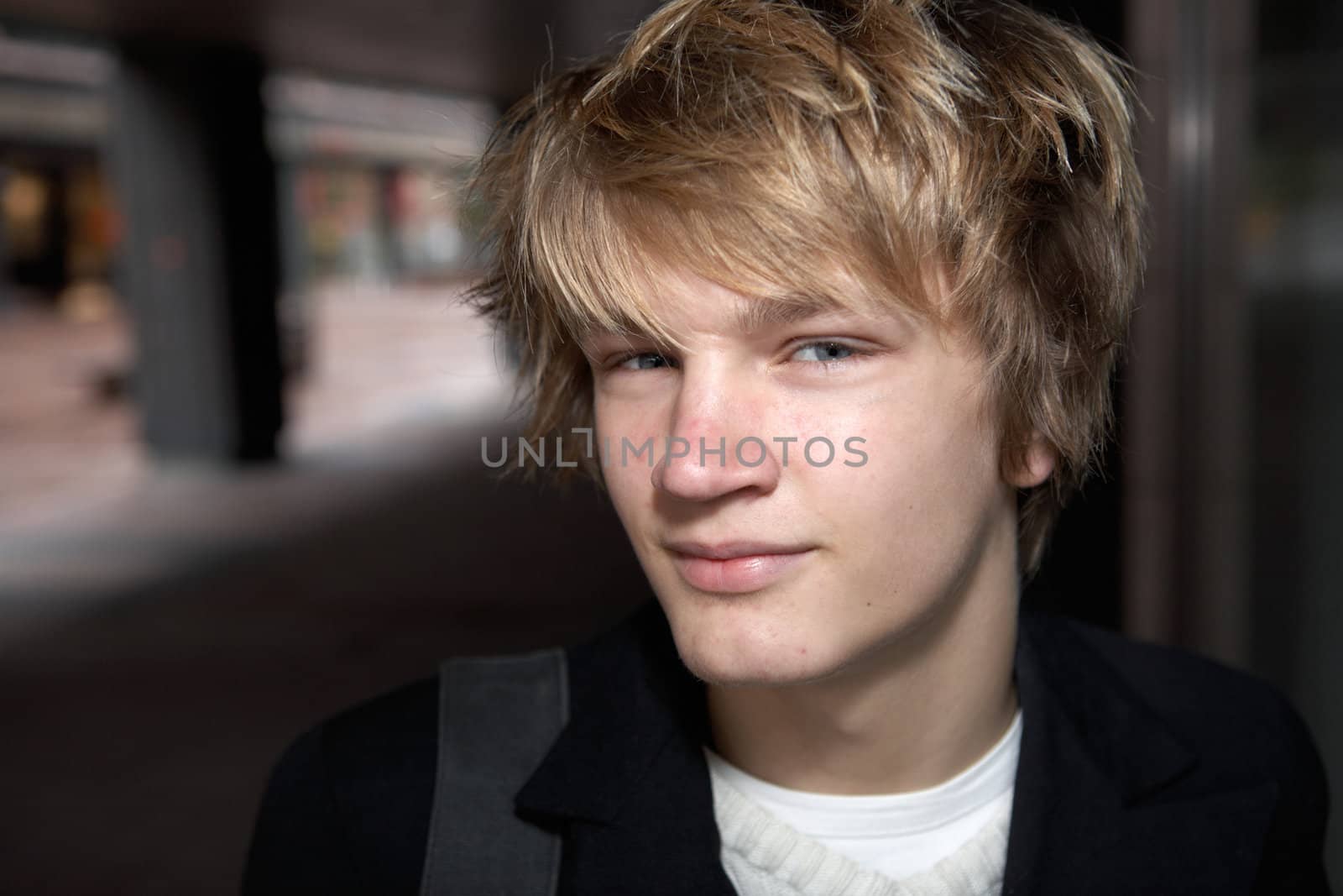 Portrait of teenage boy smiling in city street, looking at camera