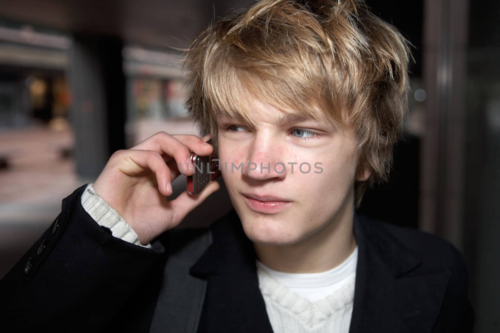 Teenage boy with on mobile phone in city street