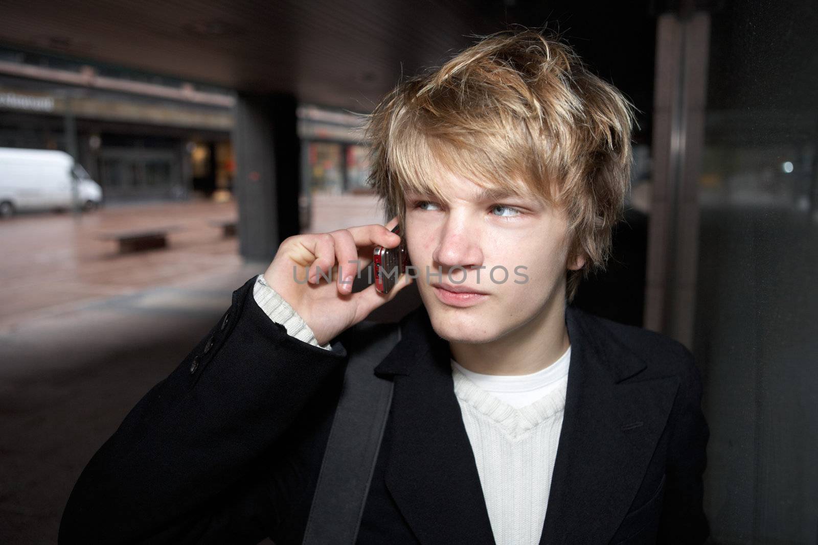 Teenage boy holding mobile phone in city street