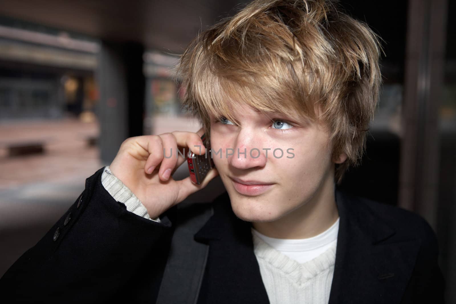 Teenage boy using mobile phone in city street