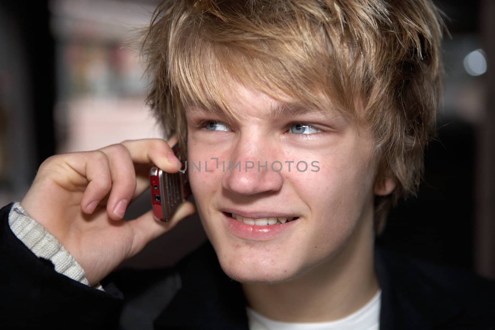 Smiling teenage boy talking on mobile phone in city, close-up