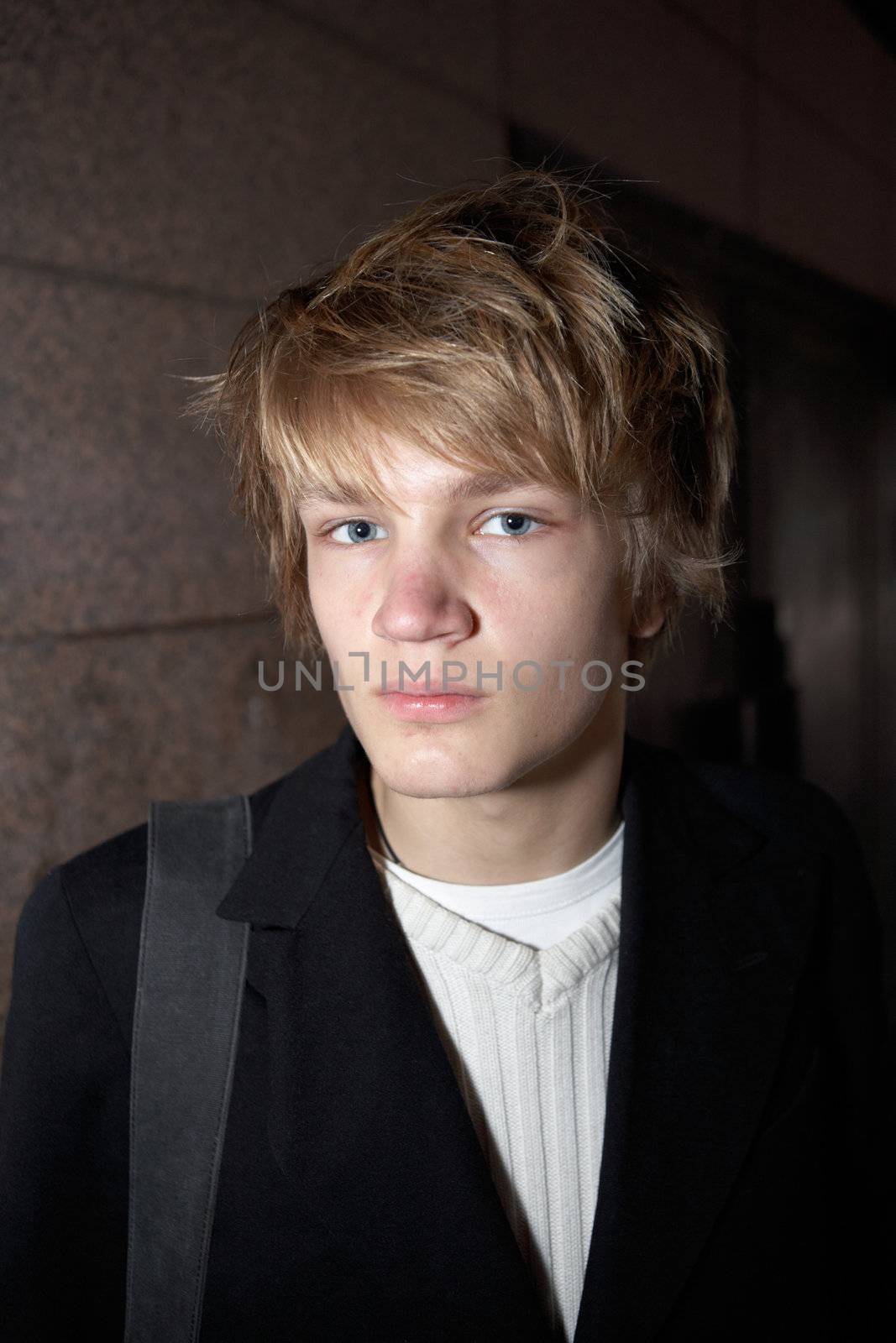 Teenage boy before building wall, looking at camera