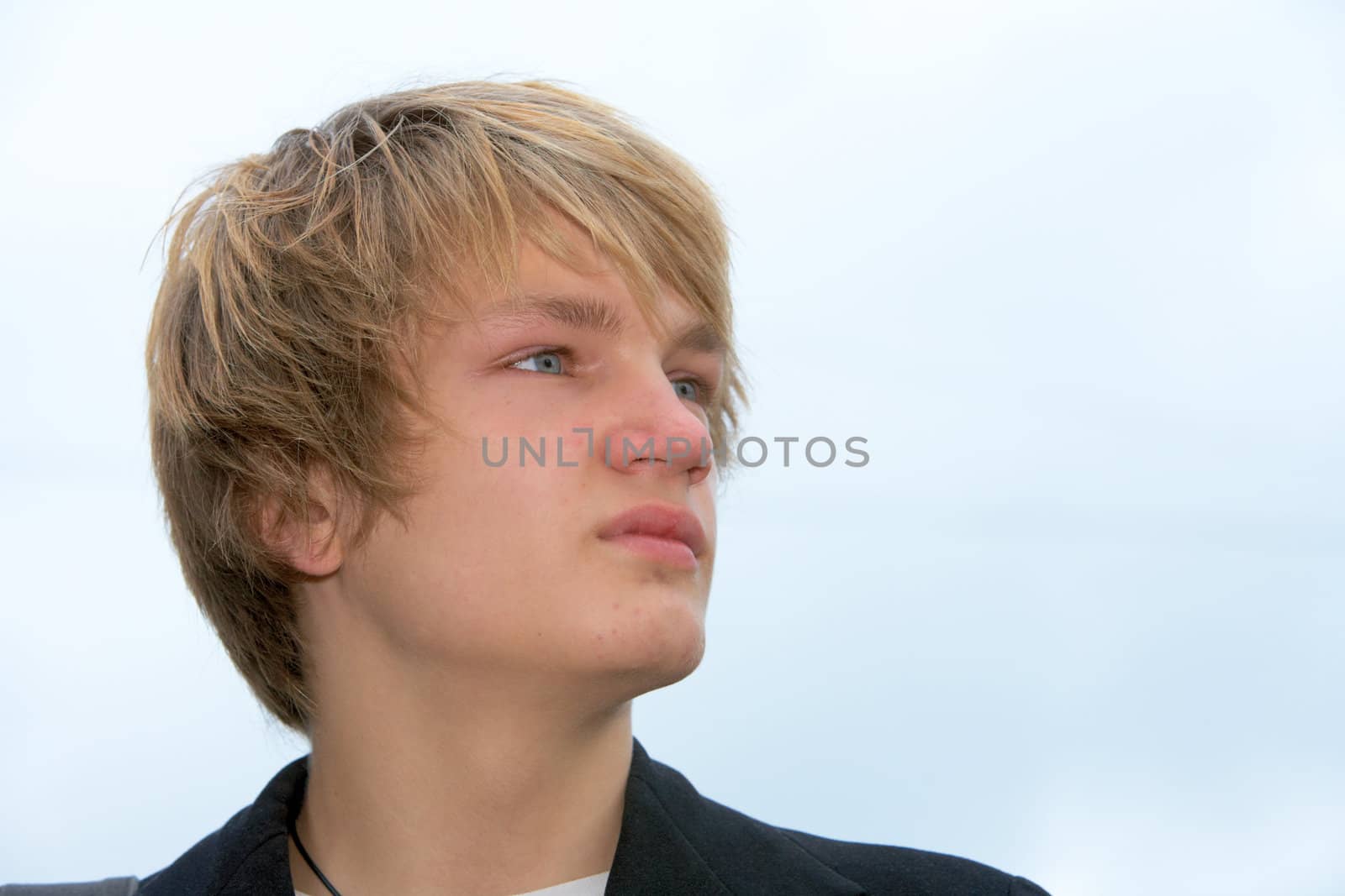 Portrait of teenage boy against sky, looking away